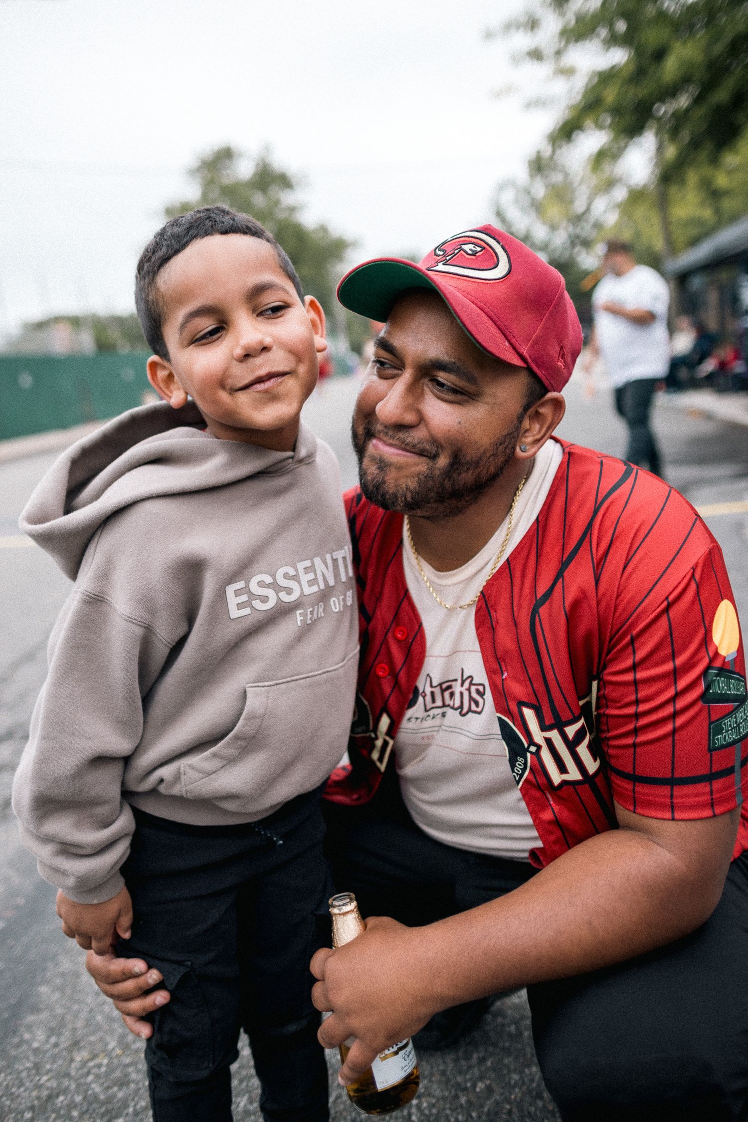 Two people sharing a warm moment while wearing casual clothing and a red baseball cap outdoors.