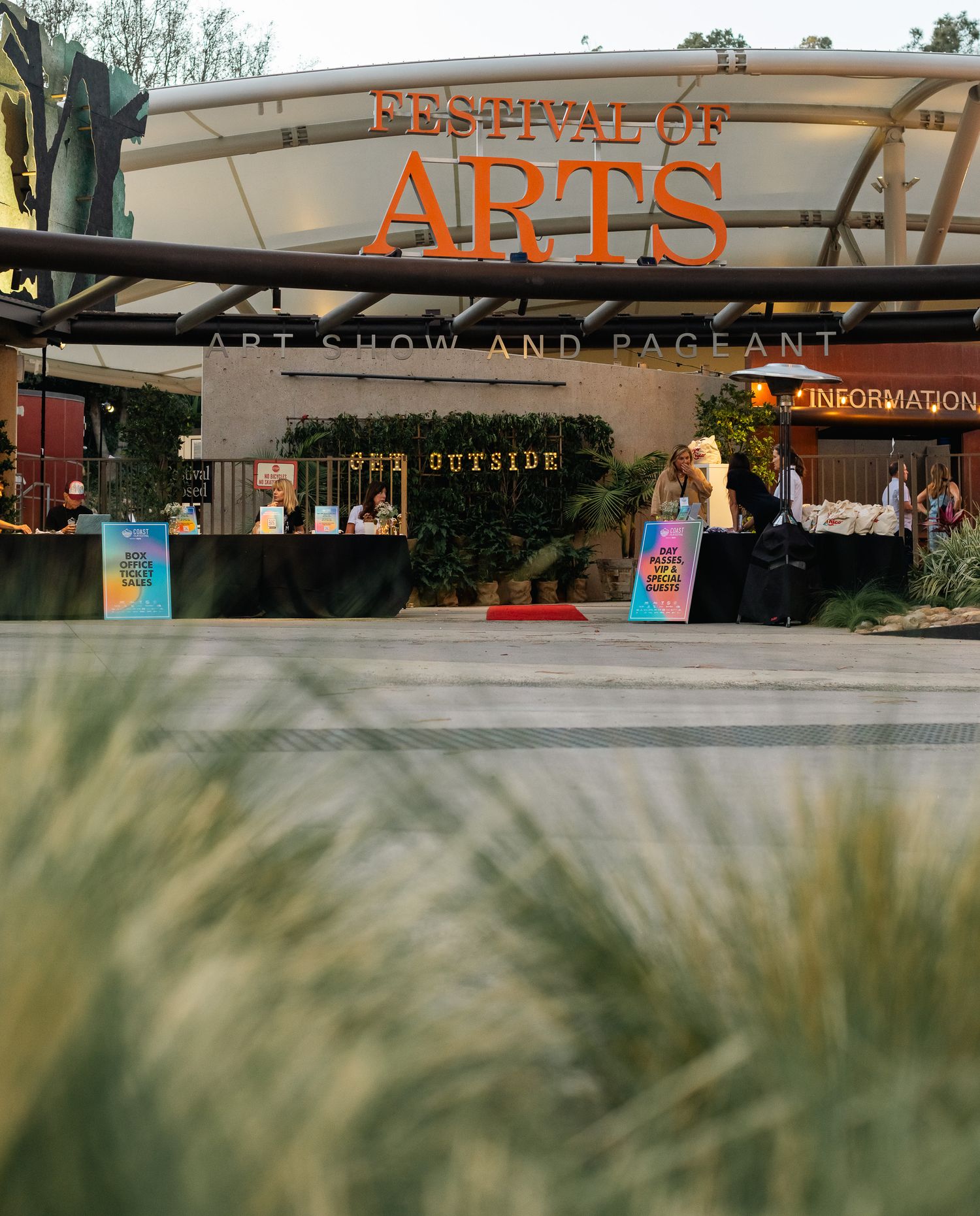 Outdoor event setup with Arts signage visible through tall grass in foreground.