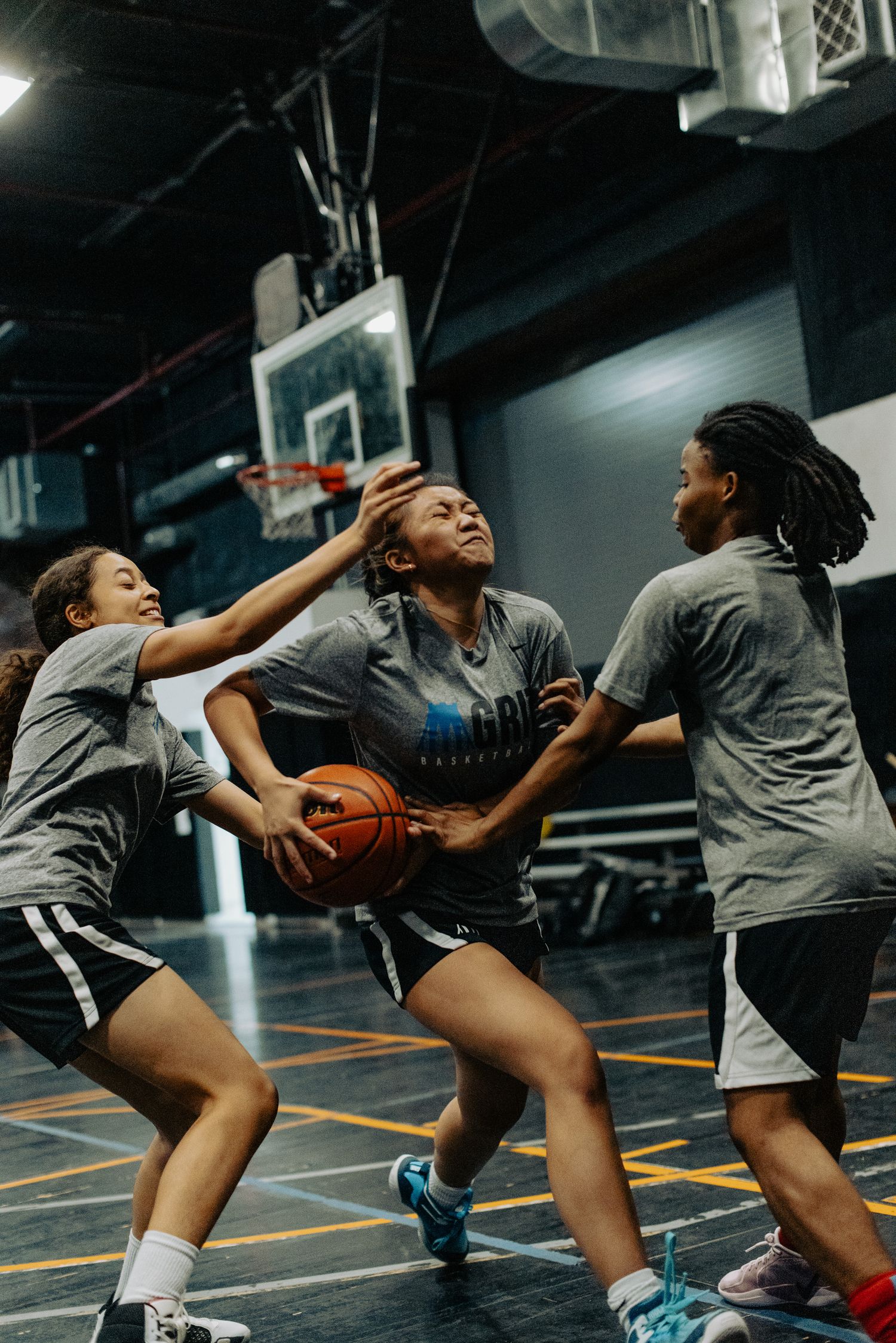 Athletes compete for possession of the basketball during an intense indoor game.