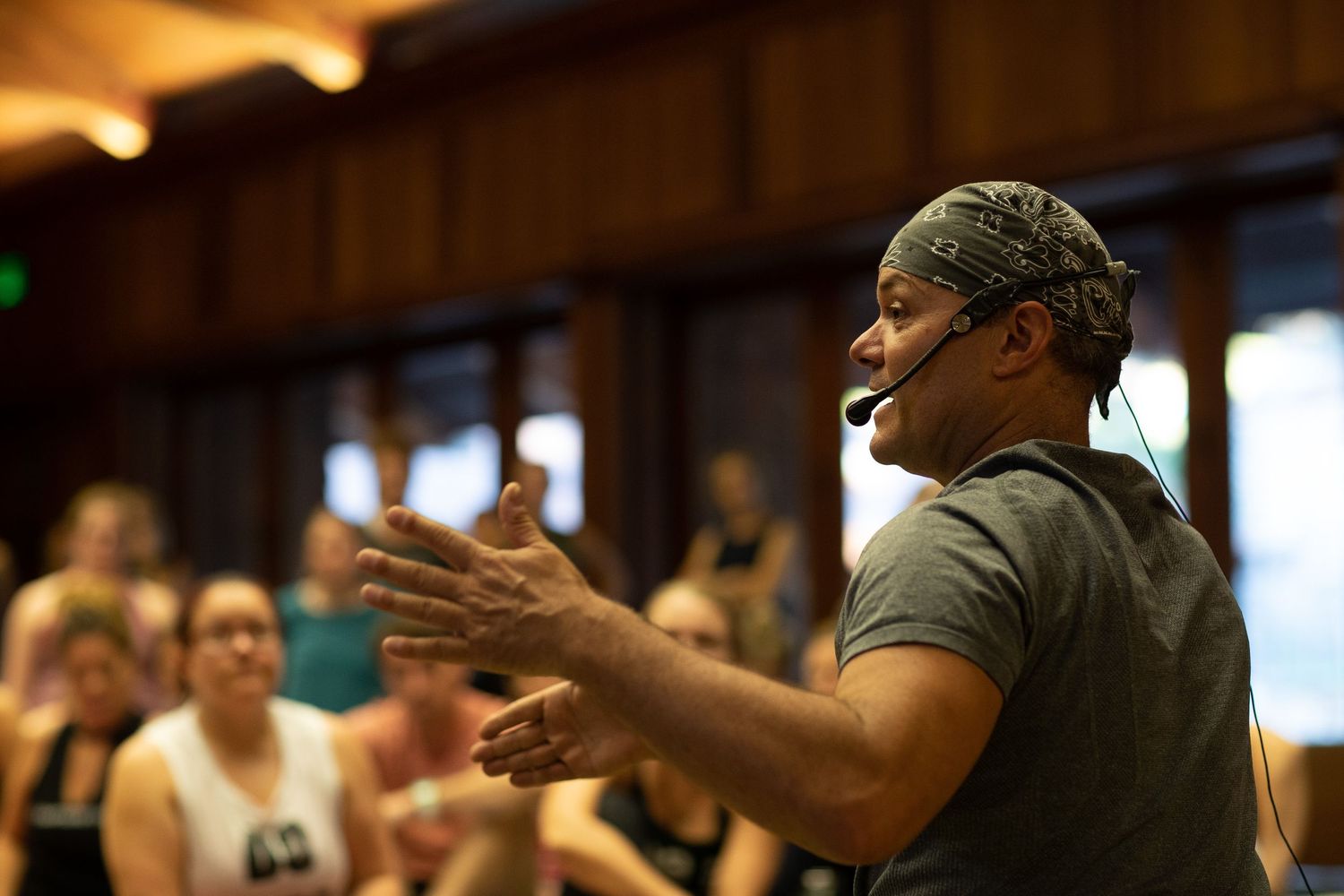 An enthusiastic instructor gestures animatedly while leading a workshop in a wood-paneled room.