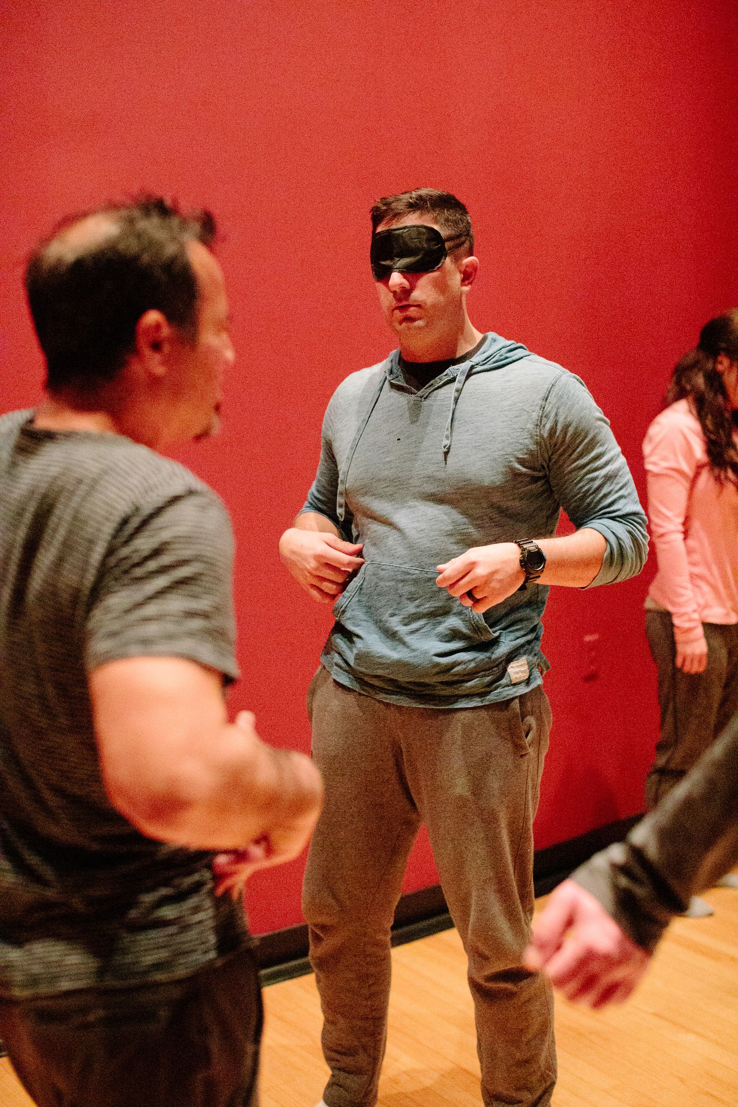People participating in physical training exercises against a red wall background.