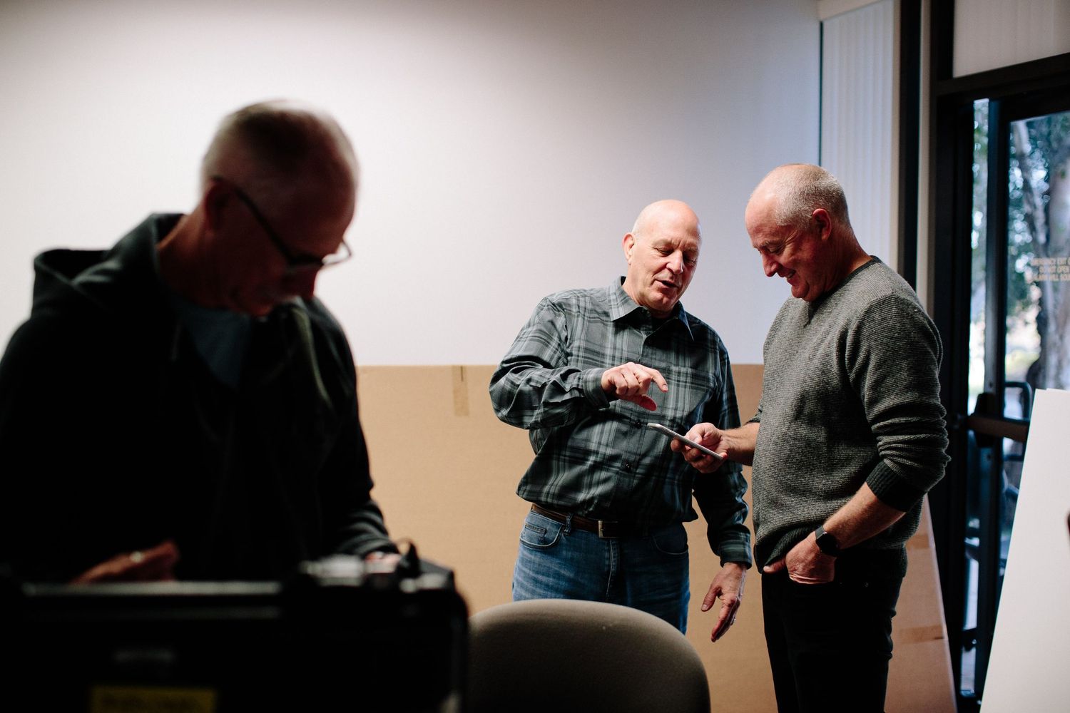 People gathered in a meeting room with soft lighting and beige walls.