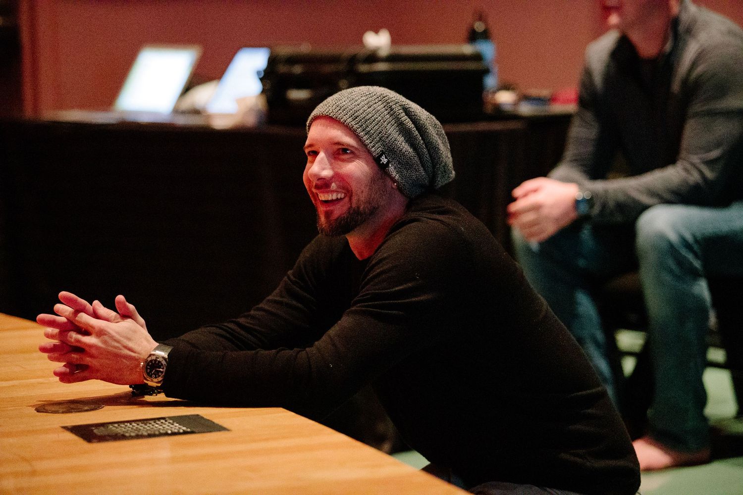 Workshop participant in grey beanie having animated discussion during indoor session.