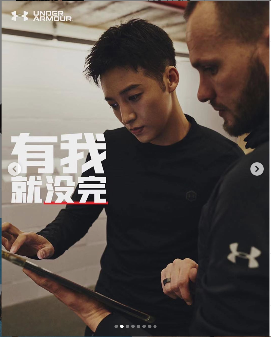 A person wearing a black Under Armour sweatshirt looks at a smartphone in a dimly lit room.
