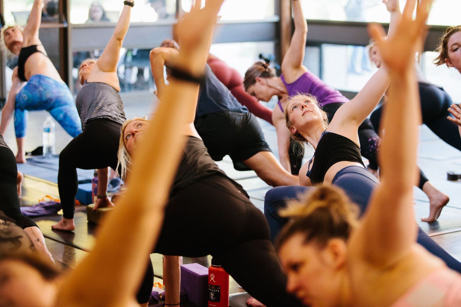 Yoga practitioners stretching with arms raised during an energetic group fitness session.