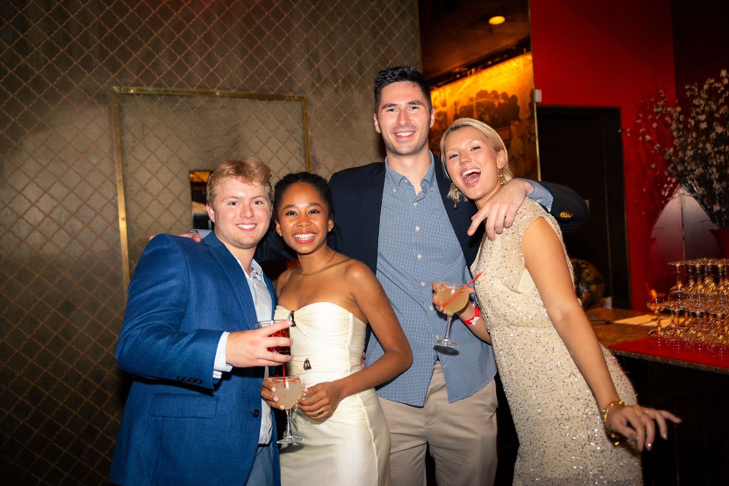 Group of formally dressed guests posing together at a social gathering.