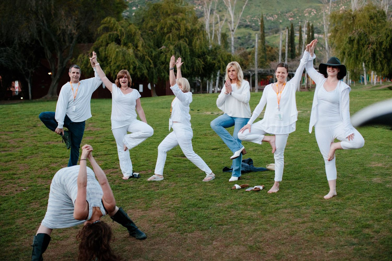 A group wearing white outfits practices Tai Chi exercises together in a park setting.