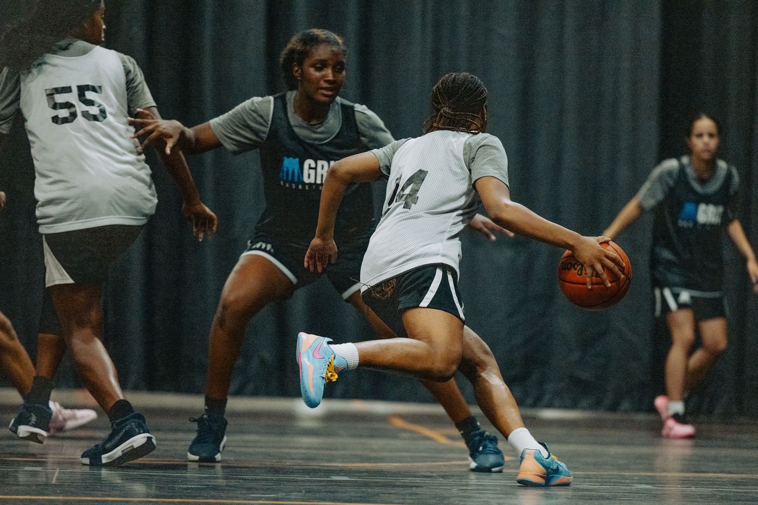 Basketball players display defensive positioning during practice drill.