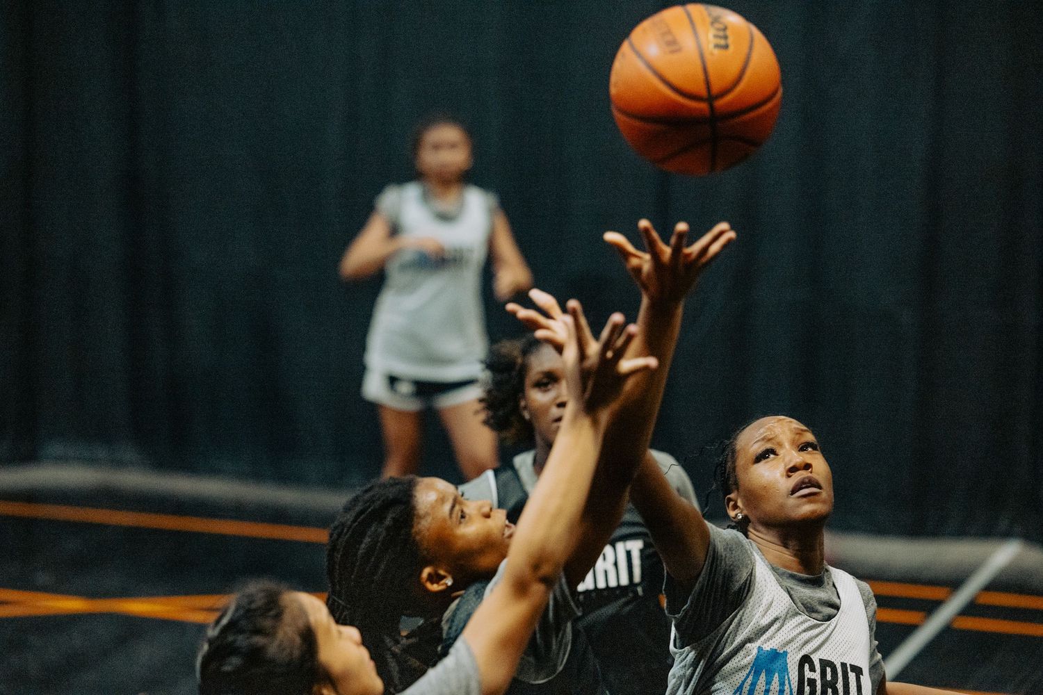 Multiple players reach for basketball during intense game action.