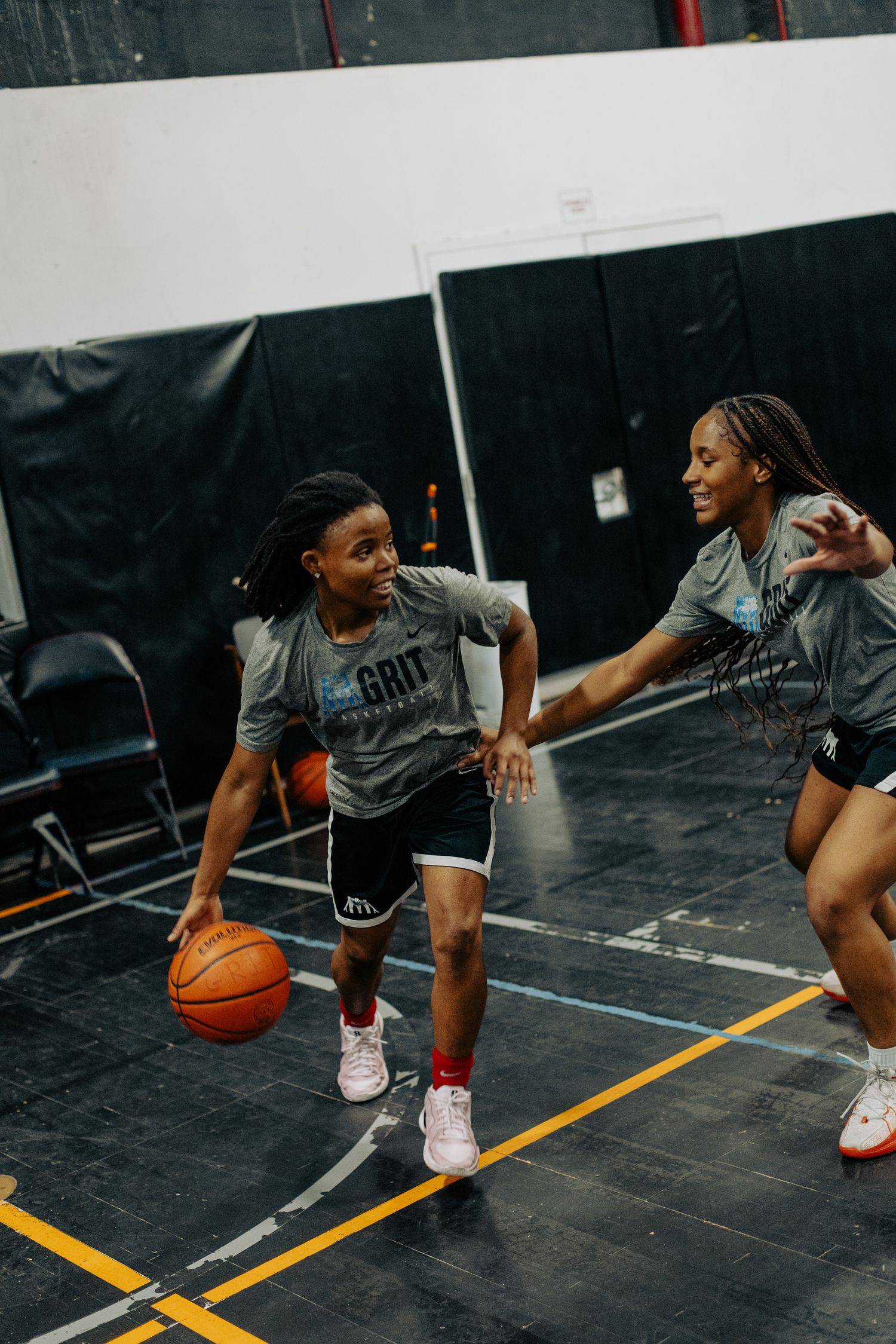 Basketball players practicing dribbling drills on an indoor court during team practice.