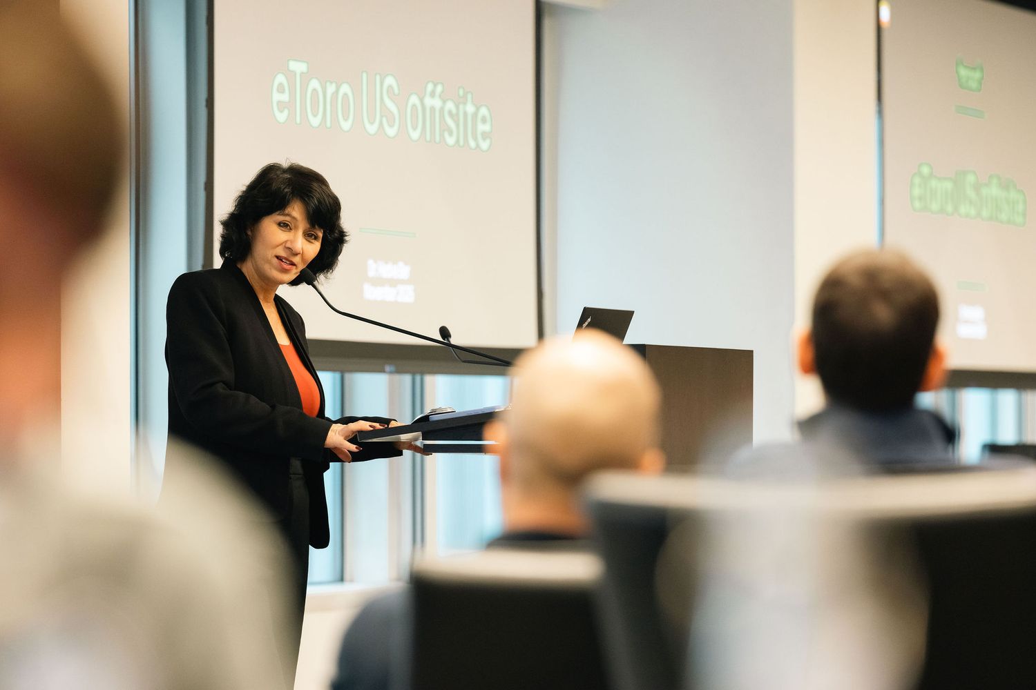 A person gives a presentation in front of a projector screen in a professional office or conference room setting.