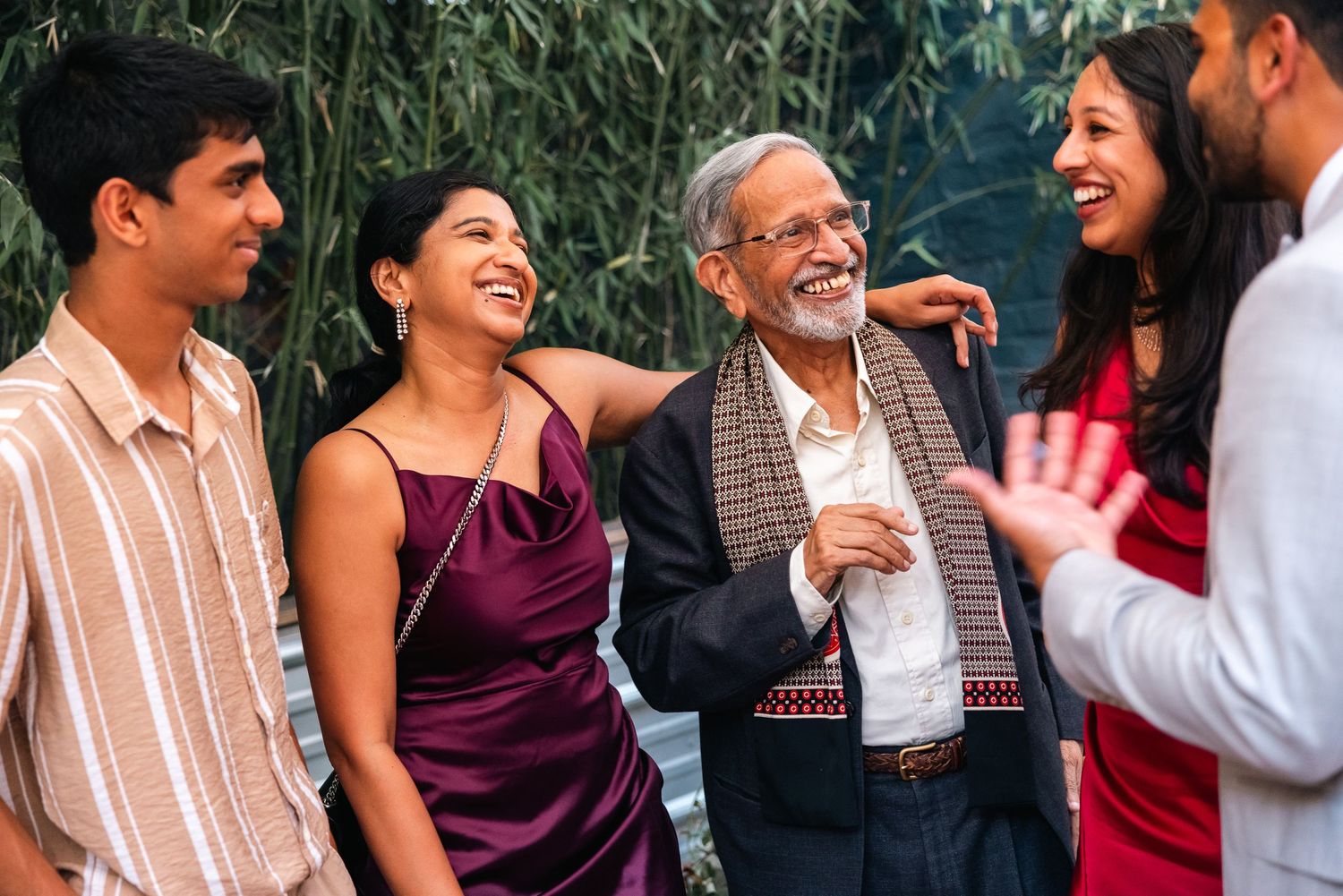 Group celebrating at an outdoor party with greenery in the background.