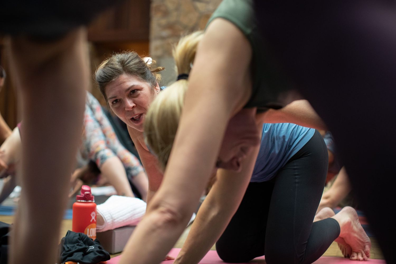 Participants smile while stretching during a group fitness class in an indoor setting.