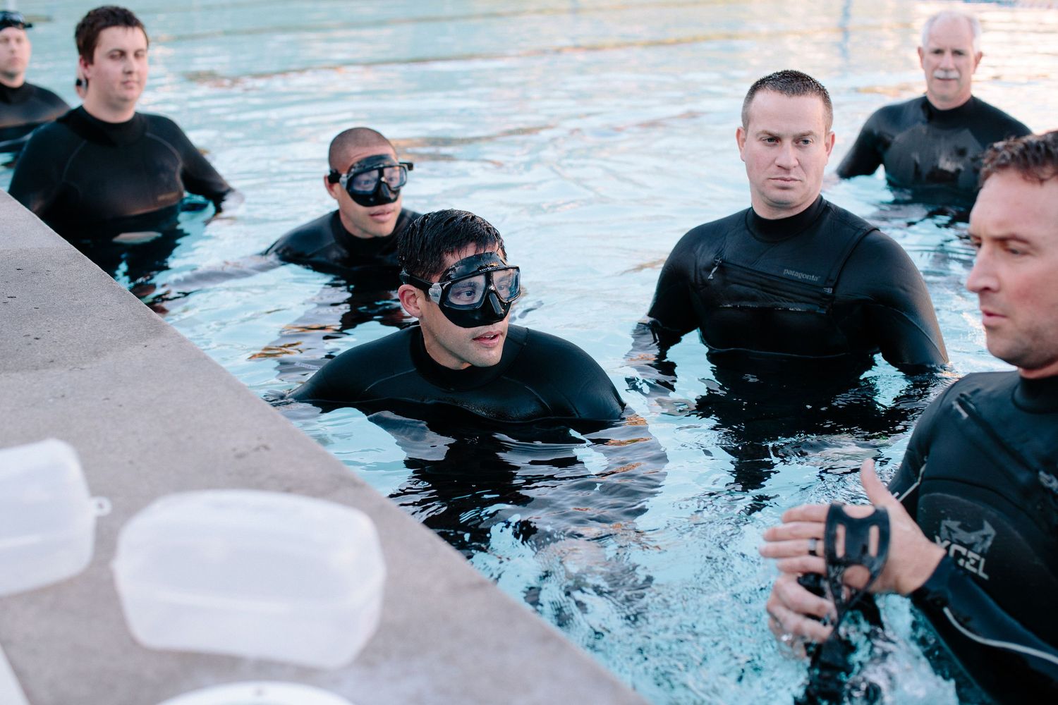Group of people in wetsuits training in a pool.