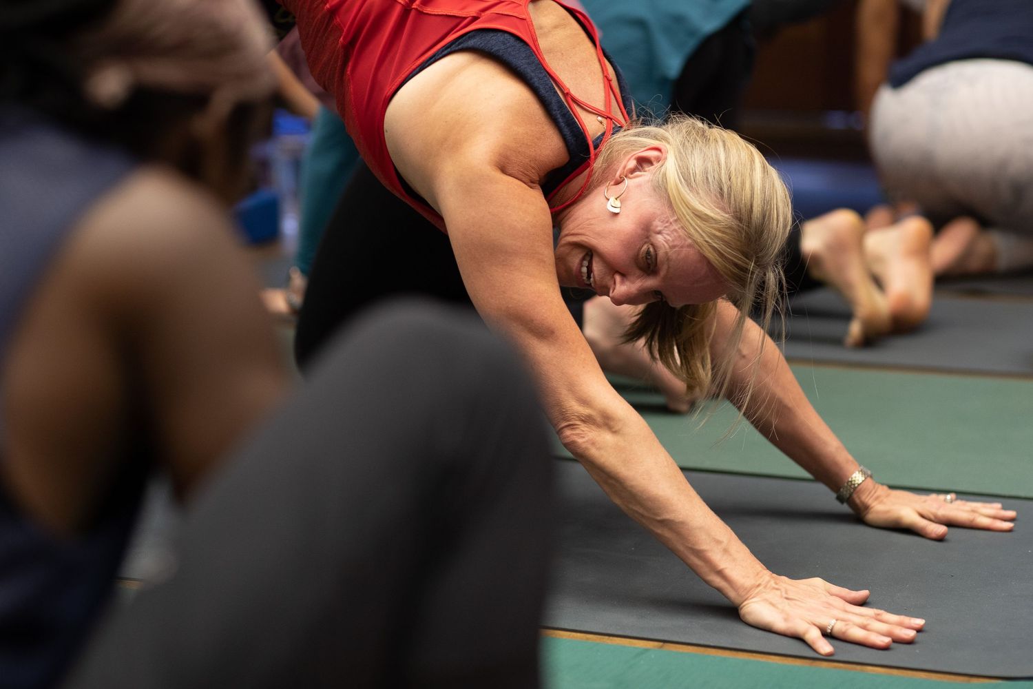 People practicing yoga poses on exercise mats in a fitness class.