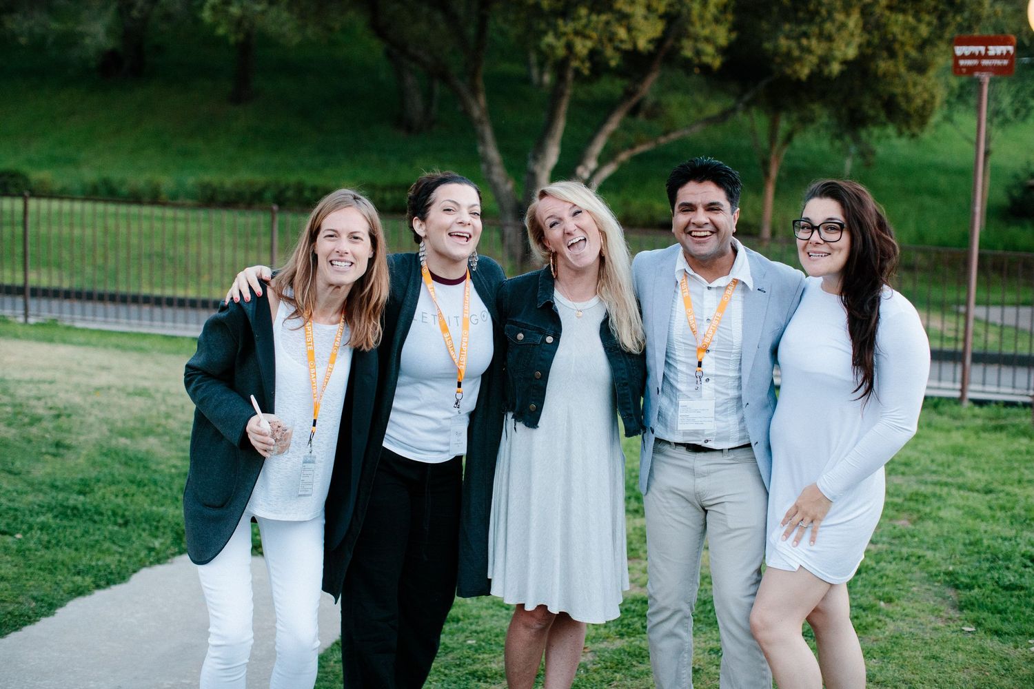 Group photo showing several individuals wearing coordinated white and black outfits on a grassy lawn.
