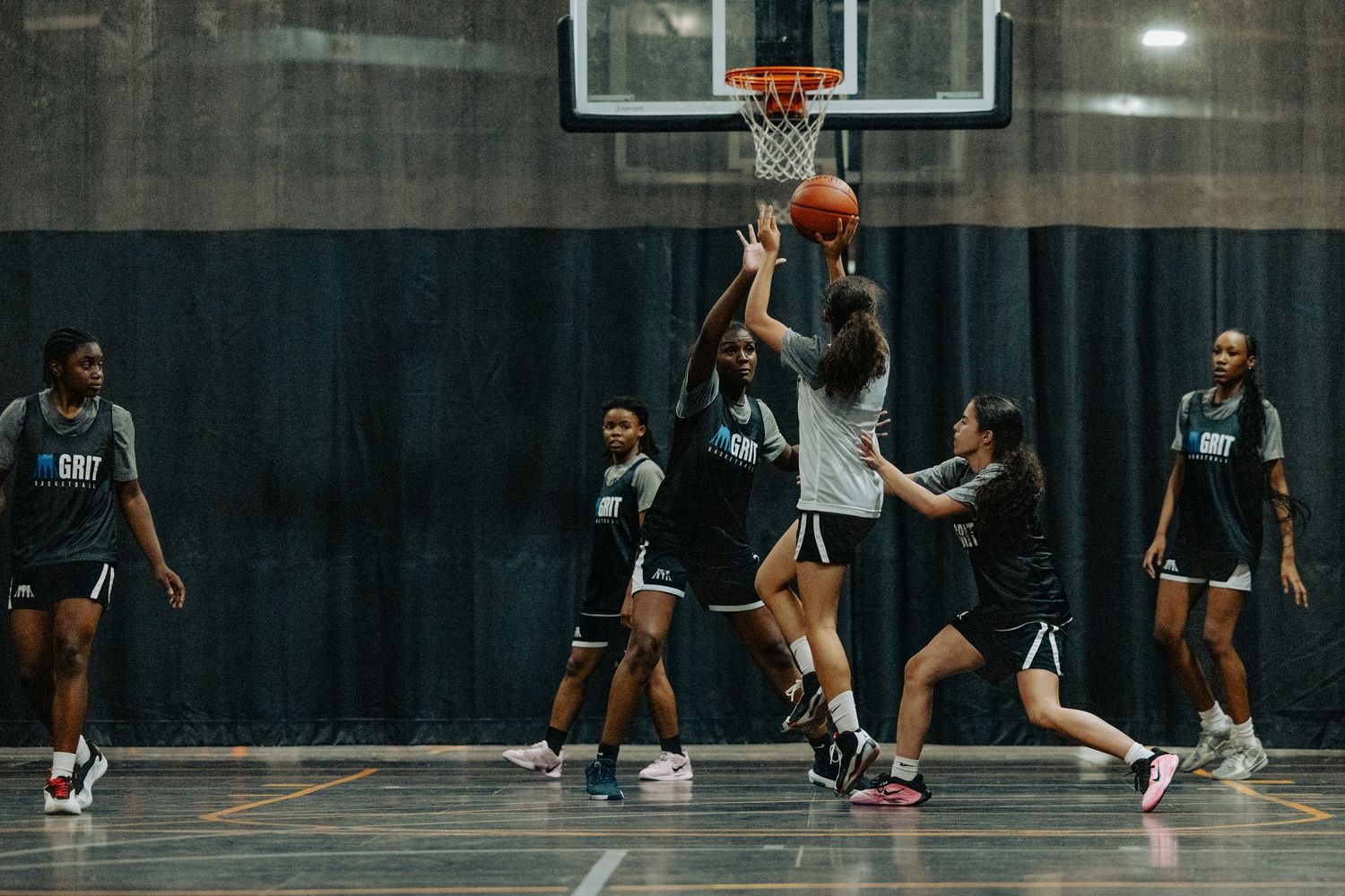Basketball players competing in a practice game on indoor court.