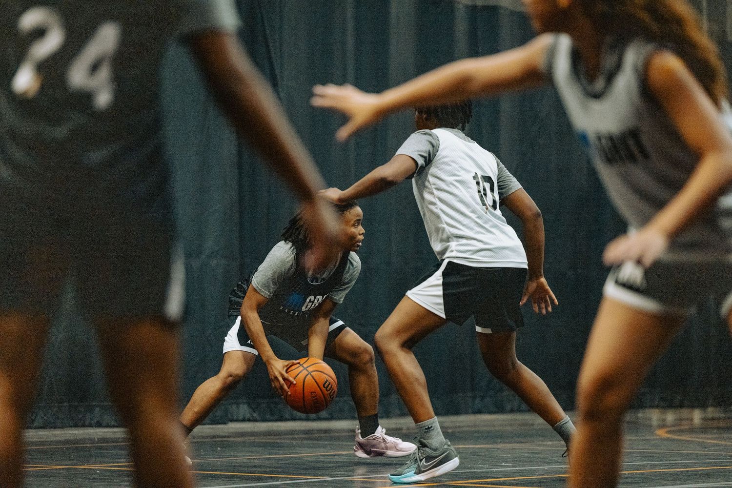 Basketball players practicing defensive stances and footwork on indoor court.