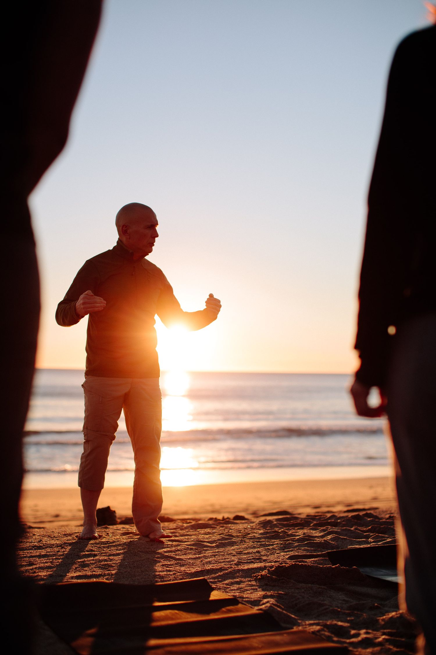 Silhouette of person giving thumbs up against sunset on beach during outdoor session.