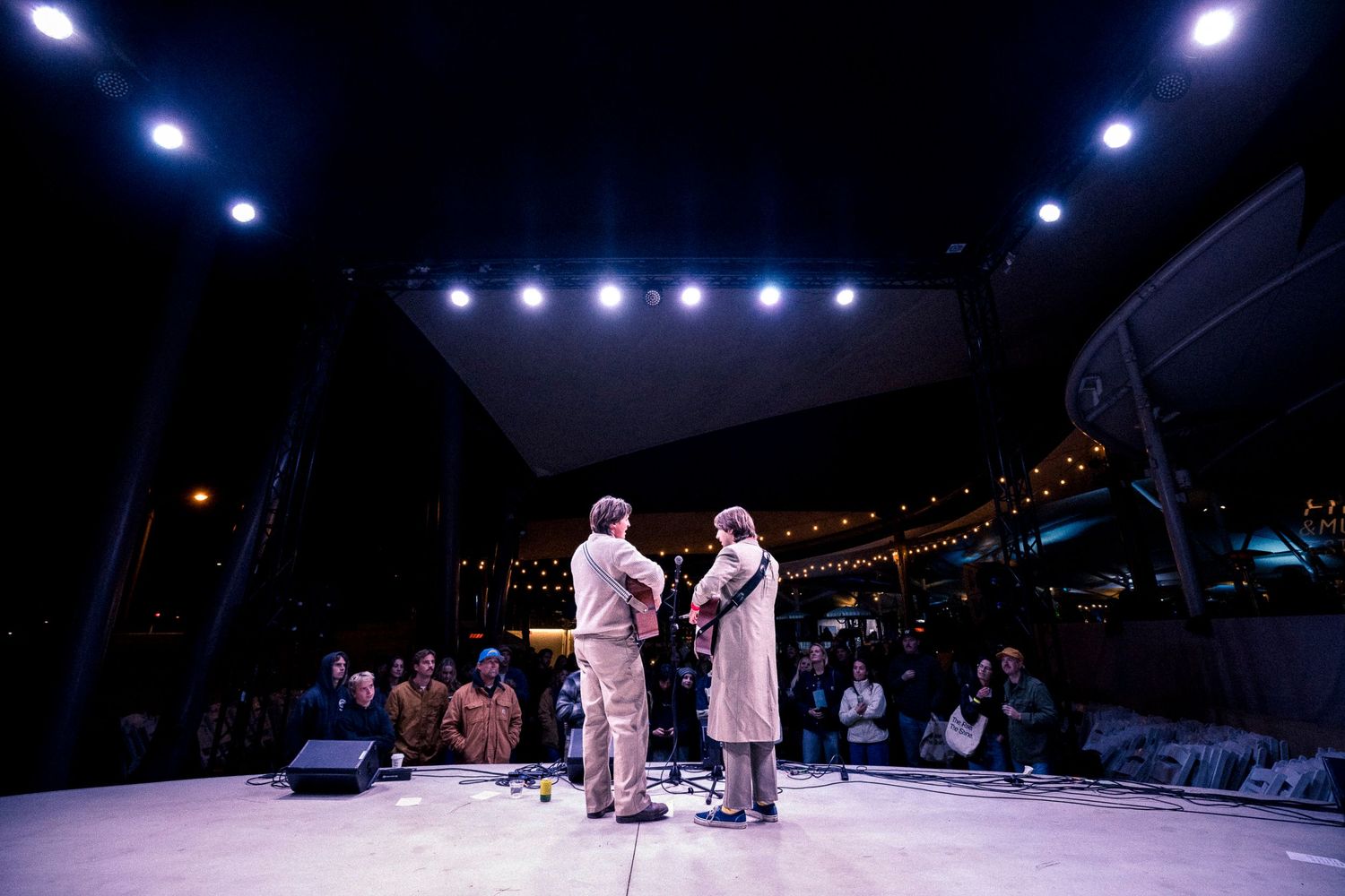 Performance on dark stage with blue spotlights and audience visible.