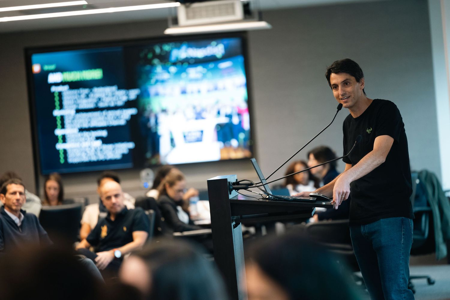 People participate in a business event with a speaker in a modern conference room with multiple display screens in New York