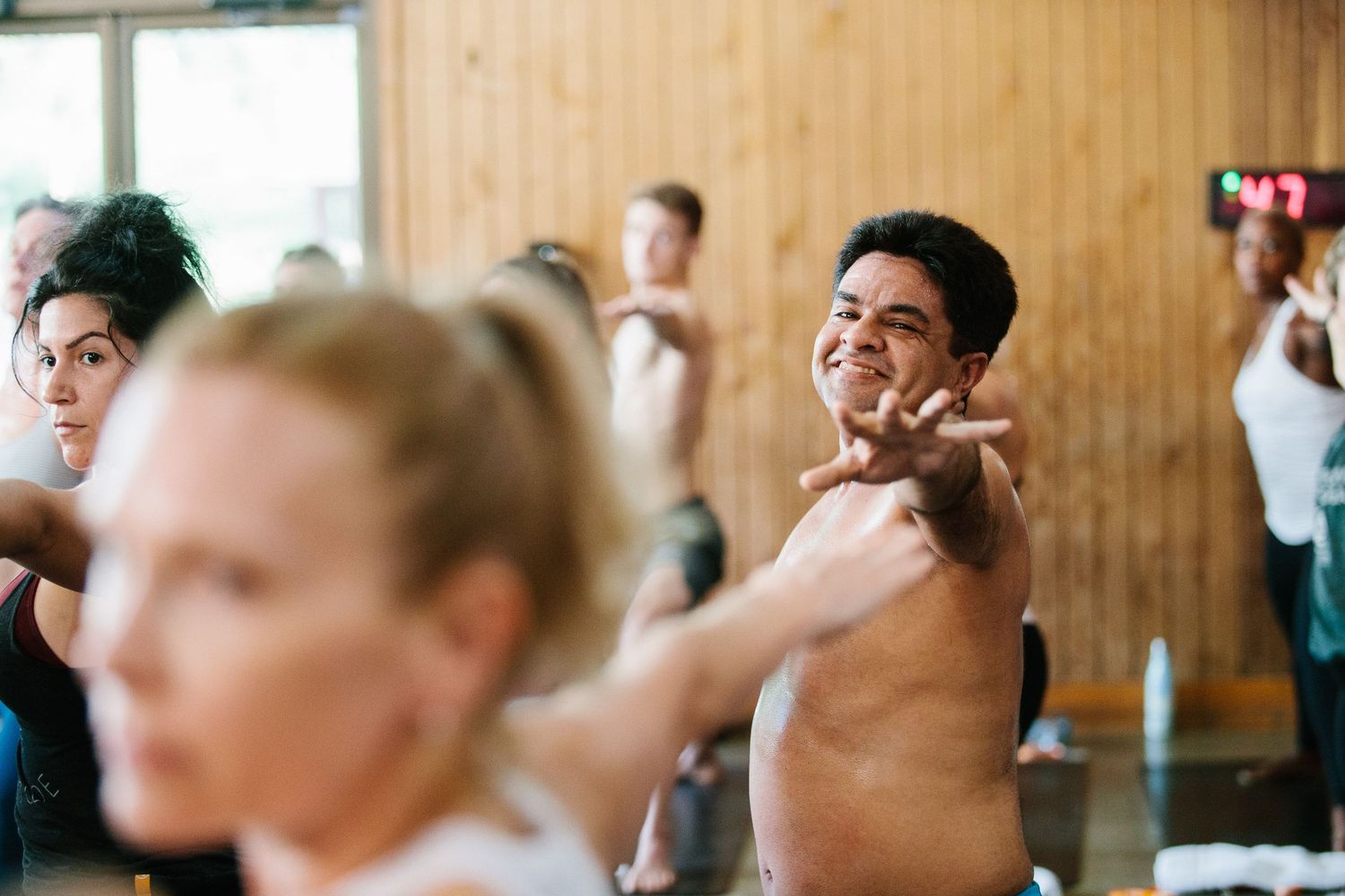 People participate in an energetic group exercise class in a wooden-walled studio.