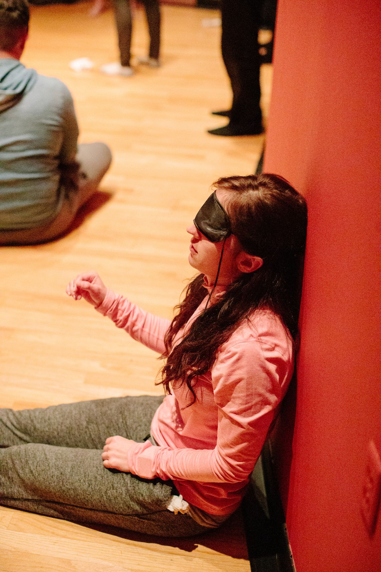 Person in pink clothing stretching or exercising against a red wall.