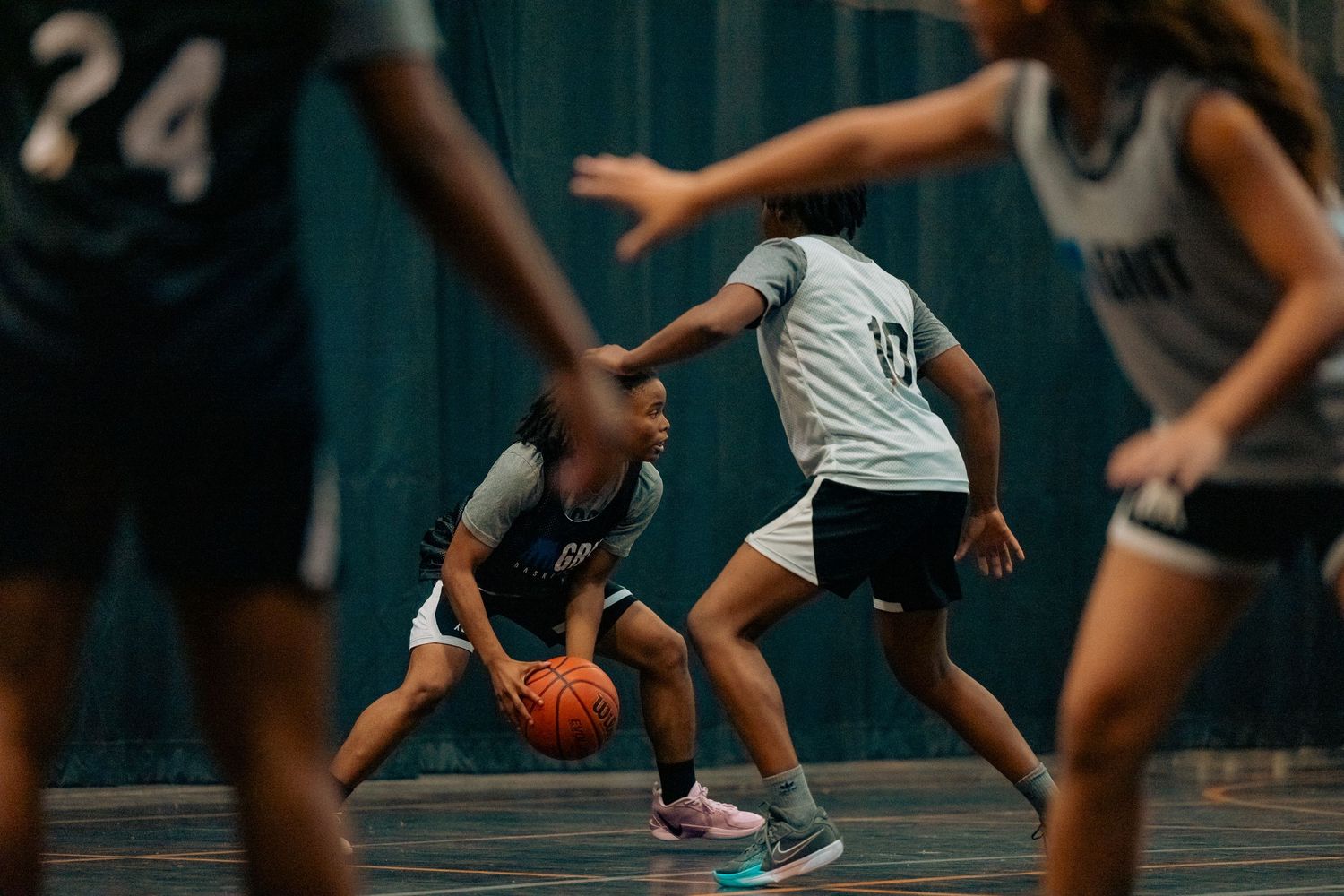 A cropped view of basketball players' legs and feet during an indoor game on a wooden court.