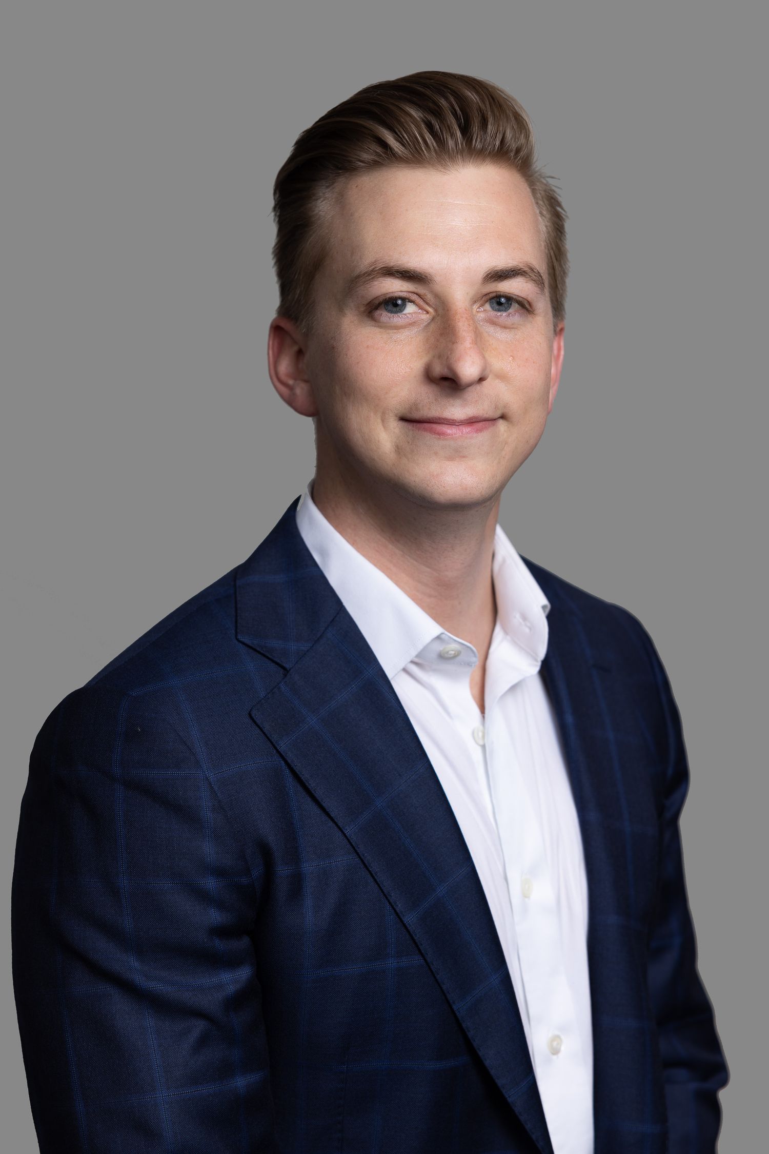 Professional headshots featuring someone in a navy suit and white shirt against grey background.