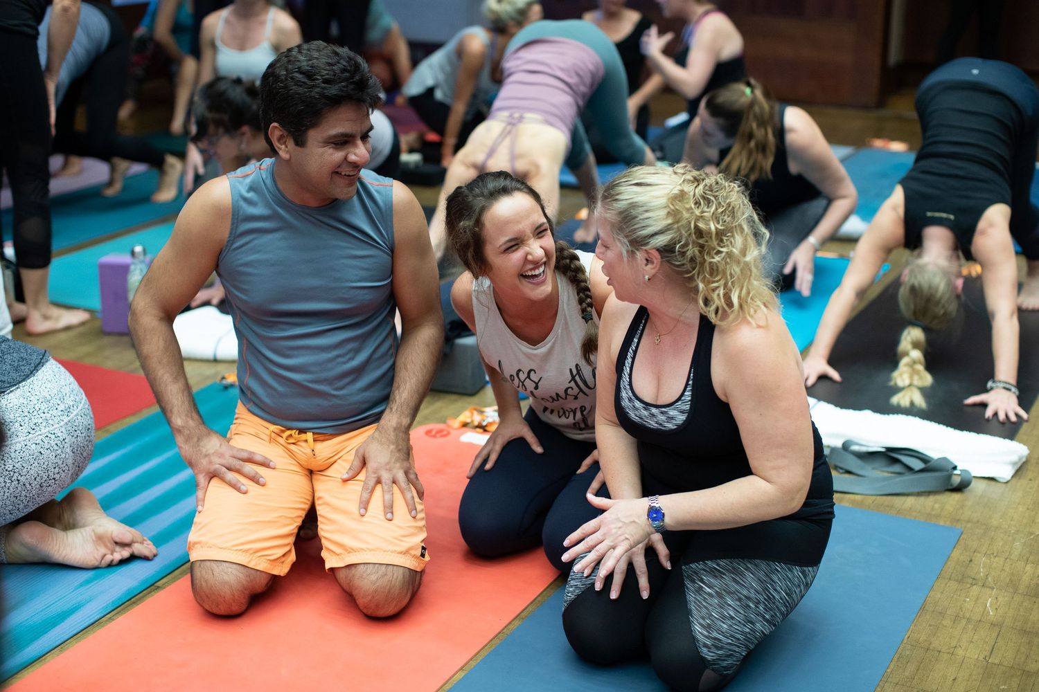 Group wellness activity participants stretch on colorful exercise mats in a studio setting.