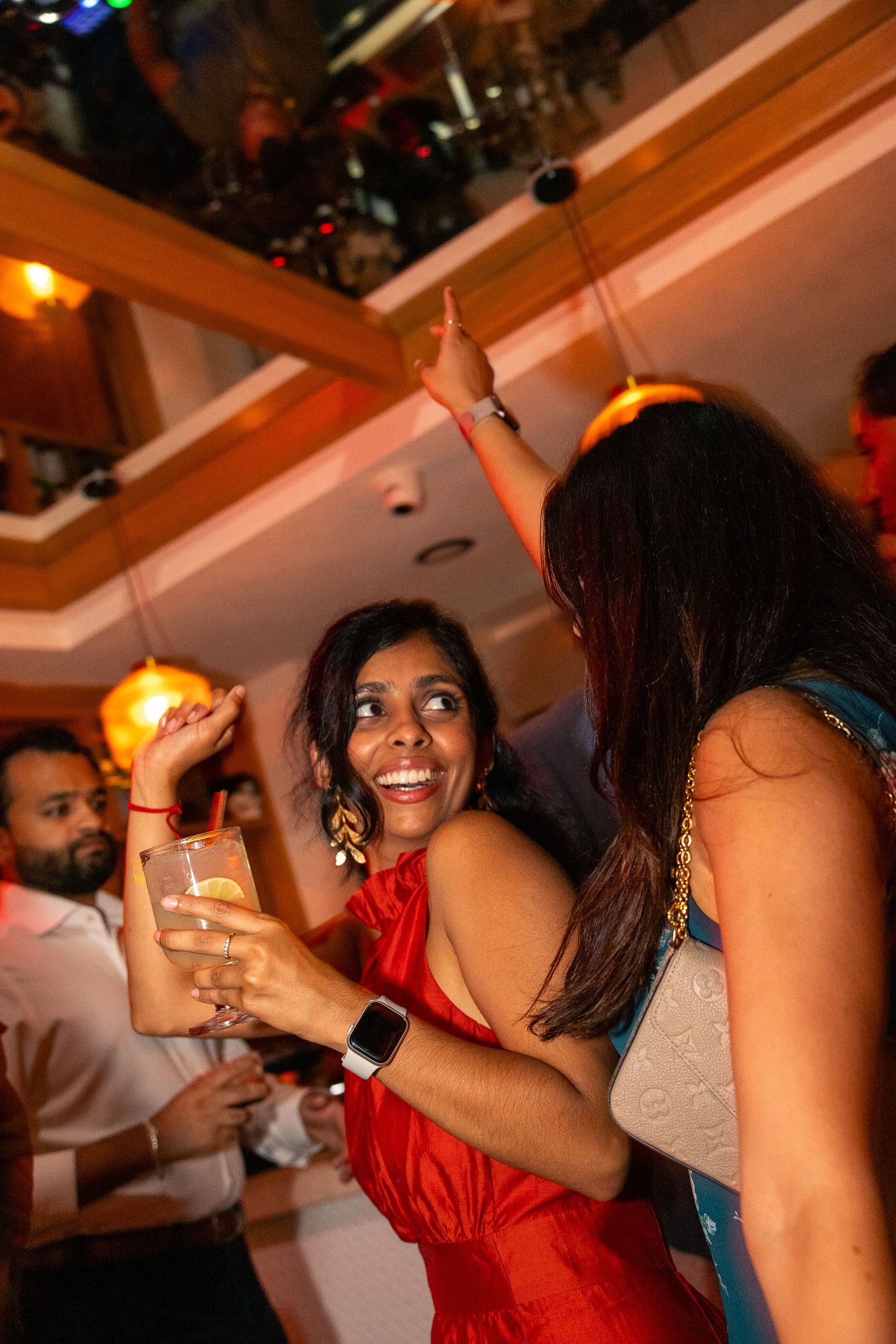 Guests dancing and celebrating with drinks under warm indoor lighting.