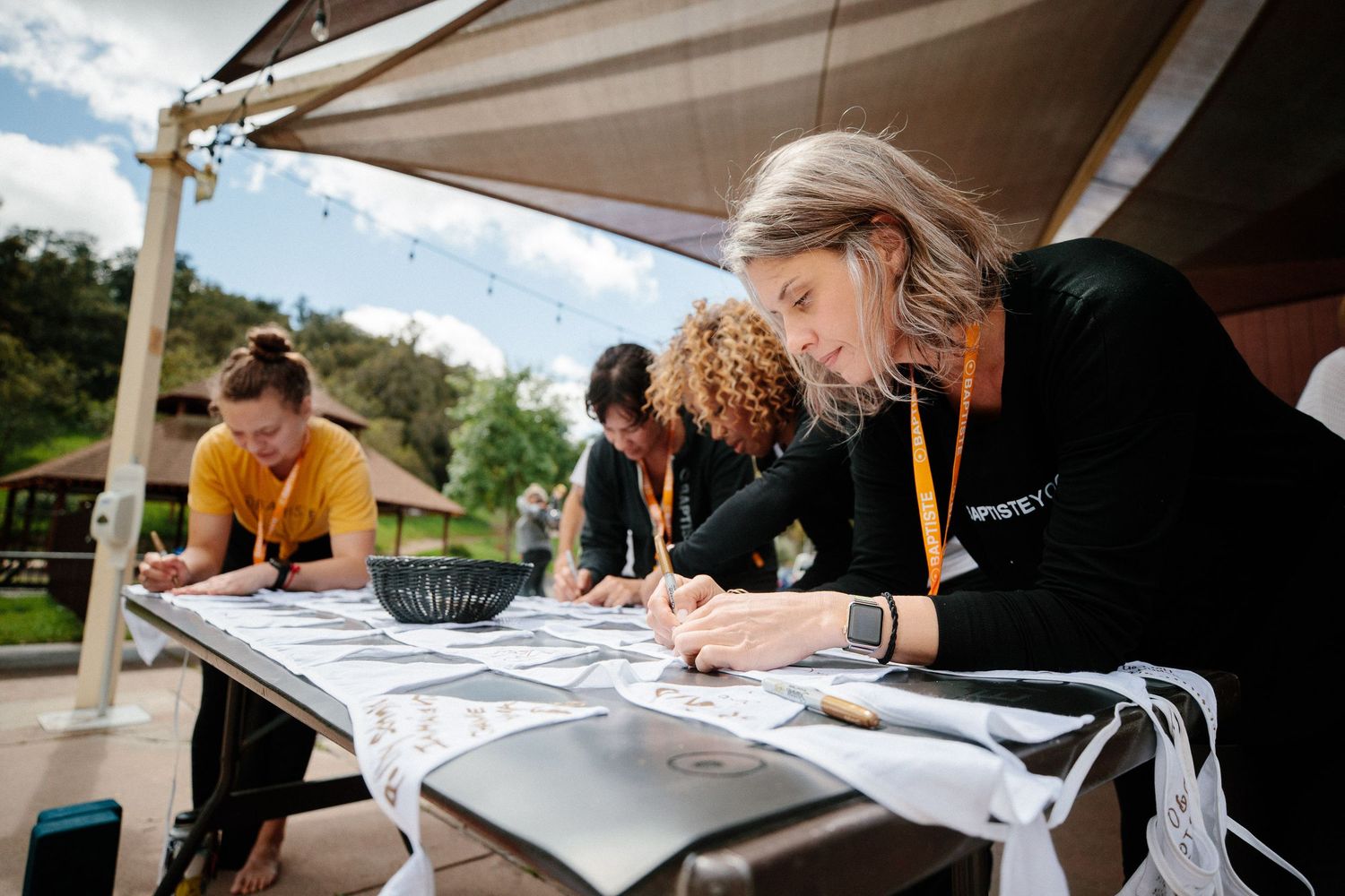 People working at tables during an outdoor workshop under cloudy skies.