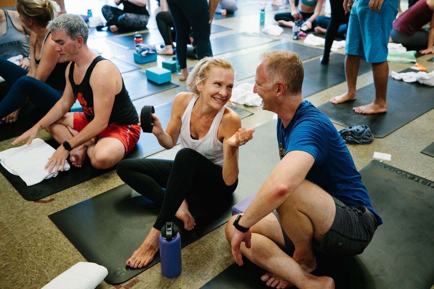 Group of people practicing partner exercises on yoga mats during a fitness class.