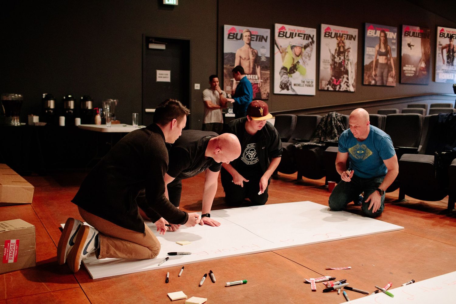 People gathered around tables working on collaborative projects in a meeting room.