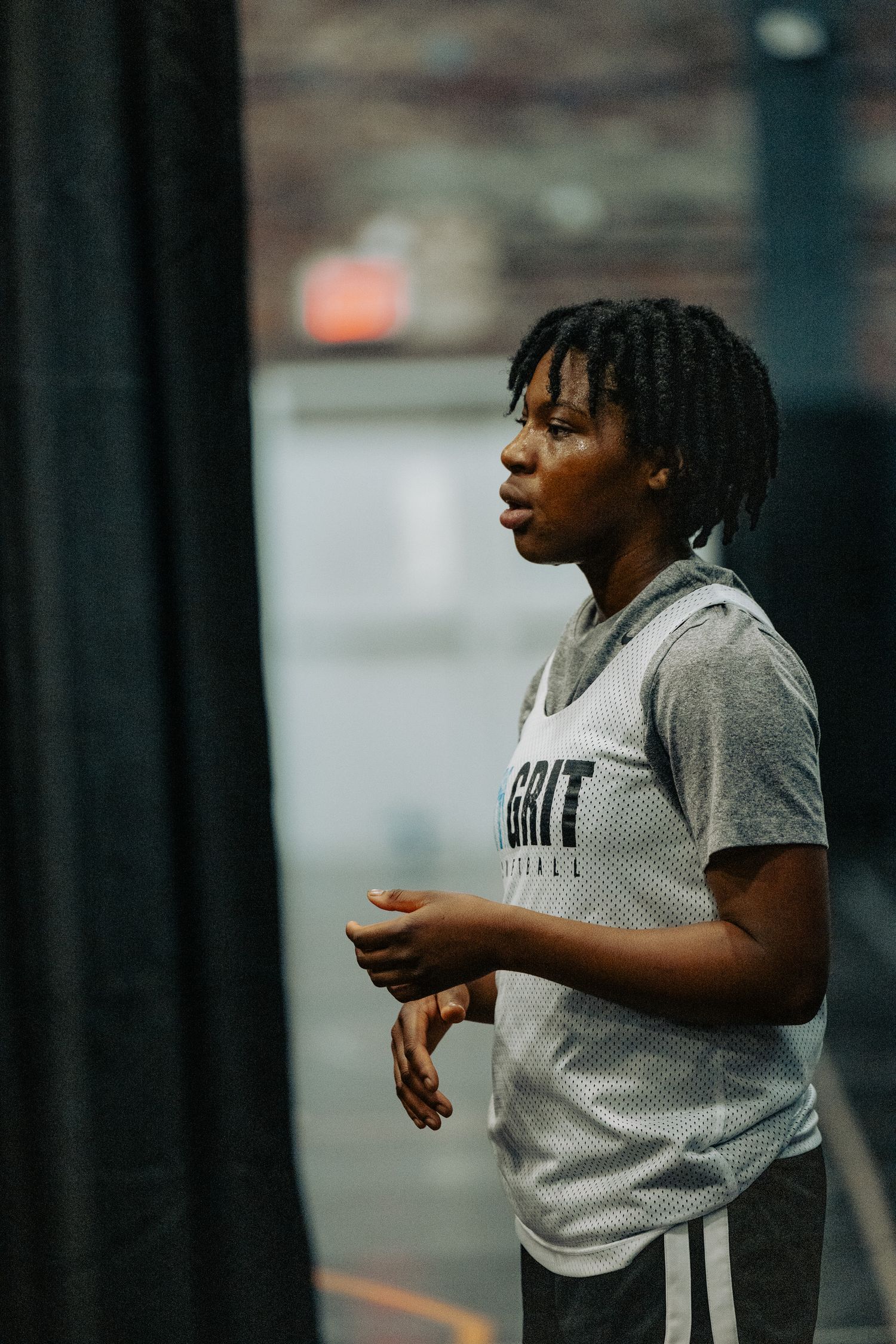 Basketball player in gray practice gear moves during an indoor training session.