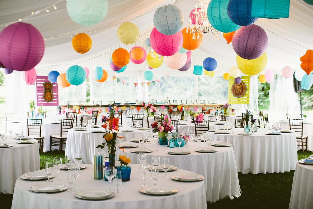 Wedding reception tent decorated with colorful paper lanterns and white tablecloths.