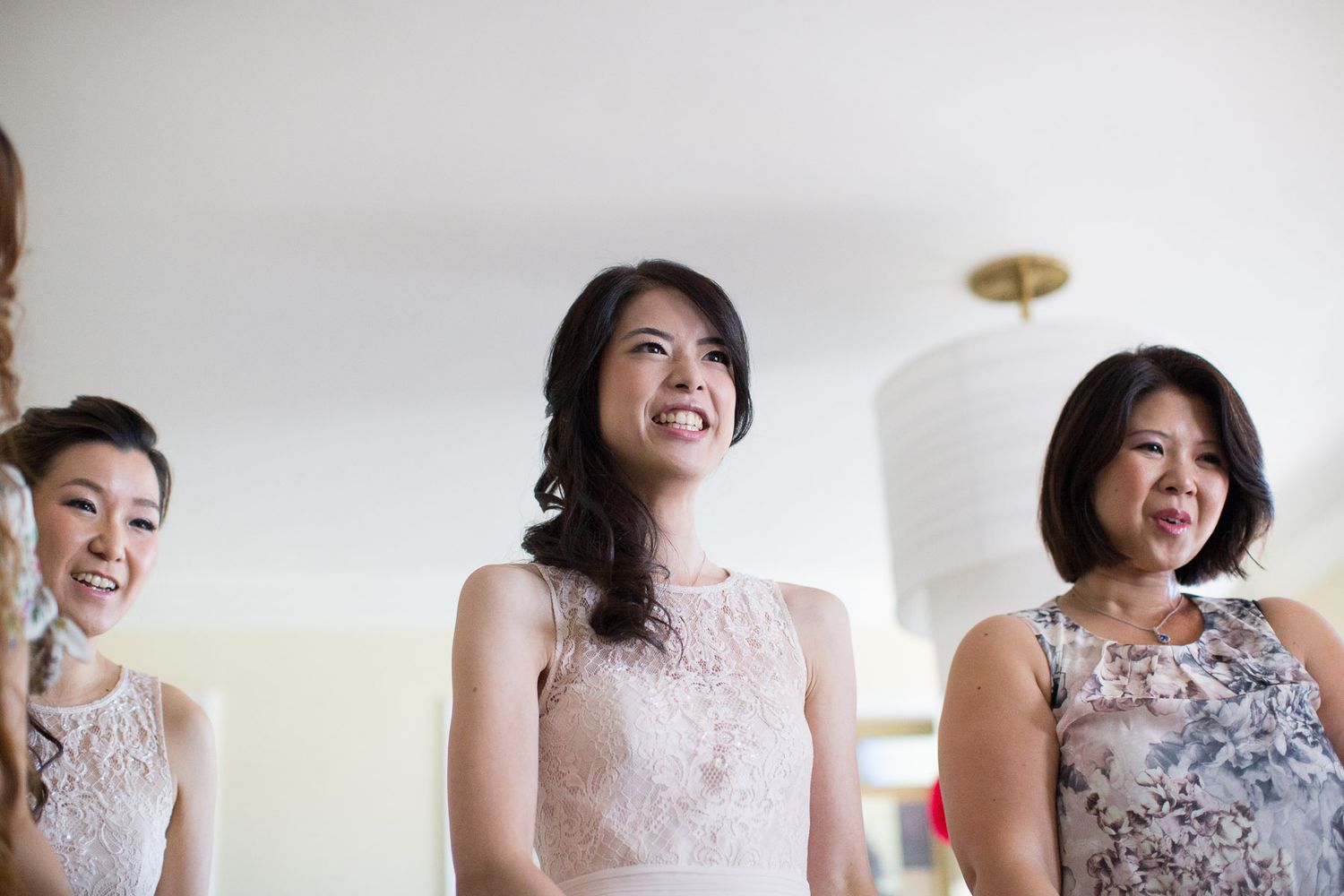Bridesmaids in delicate lace dresses share joyful expressions during wedding preparations.