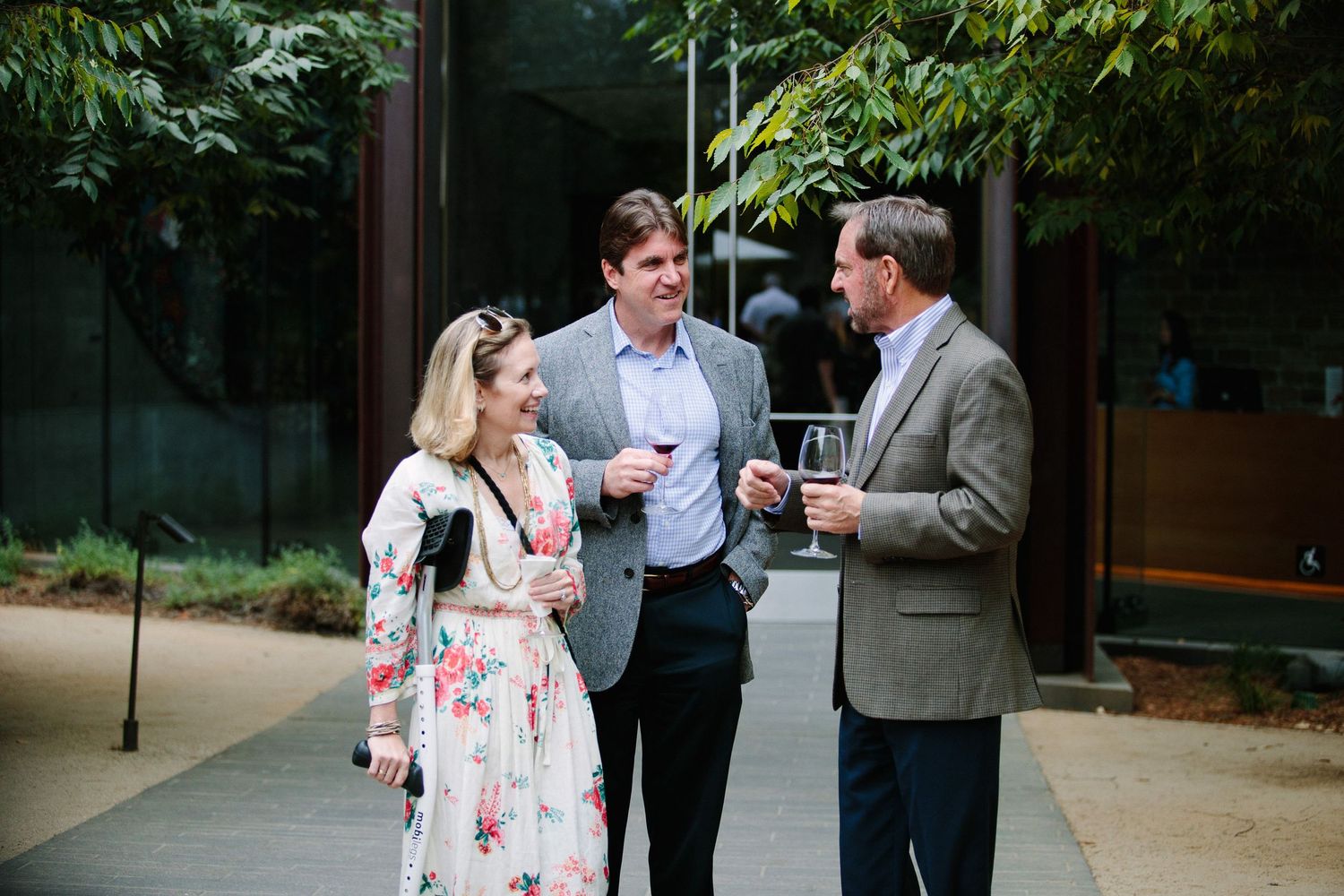 A small group chats casually outside a building entrance on a landscaped pathway.