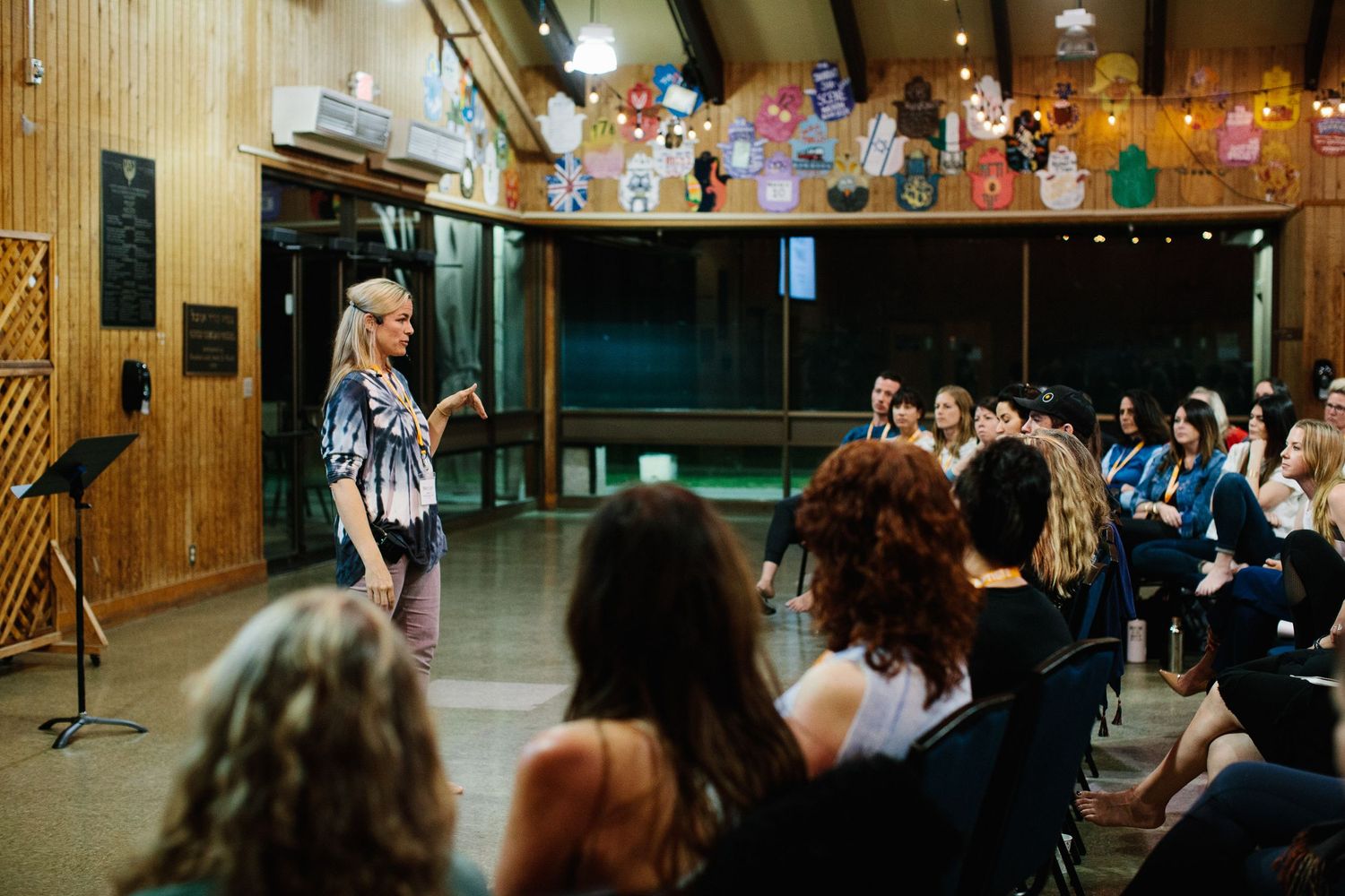 People gather inside a modern building lobby with glass walls and stone columns during what appears to be an event.