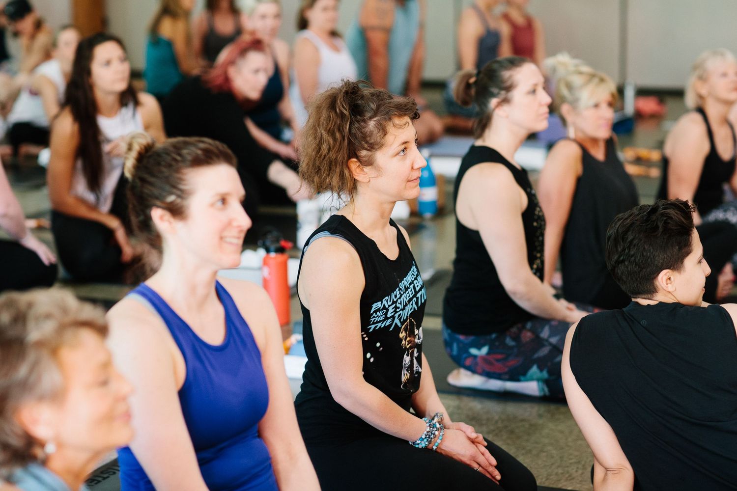 Participants in workout clothing listen attentively during a group fitness session.