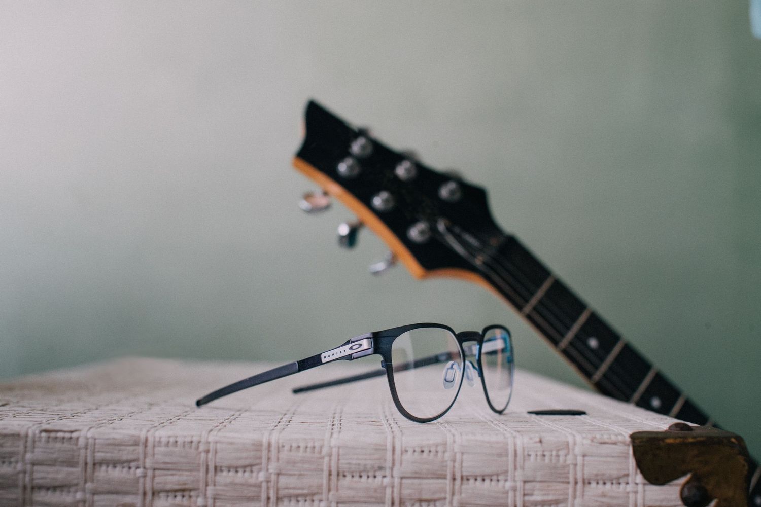 Guitar resting on a wooden surface with selective focus on Oakley sunglasses for a Oakley ad.
