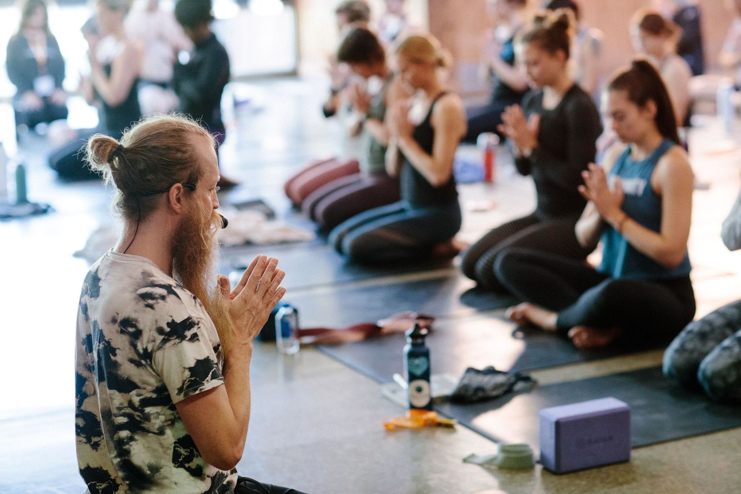 People sitting in a circle on yoga mats during an indoor wellness workshop.