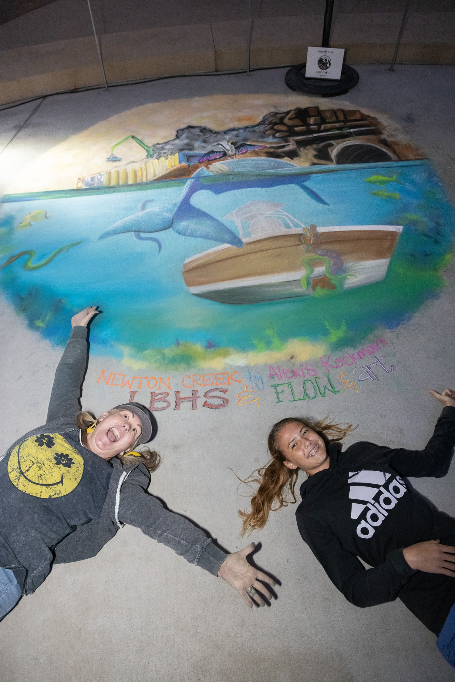 Creative floor art installation with ocean theme and people posing alongside it.