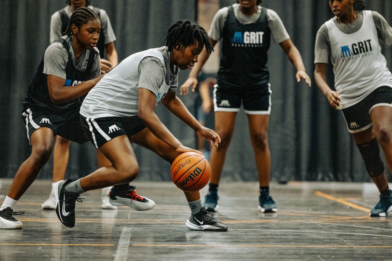 Players compete for loose basketball during intense indoor game practice session.