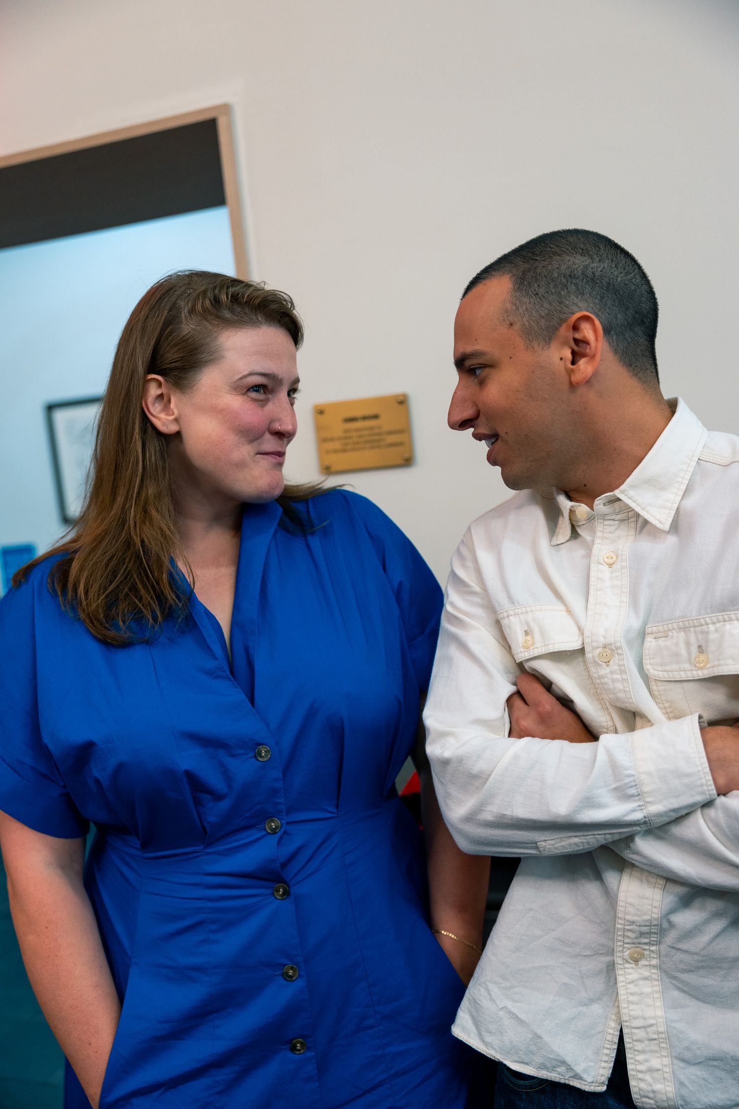 Two people in blue and white outfits having conversation by wall.