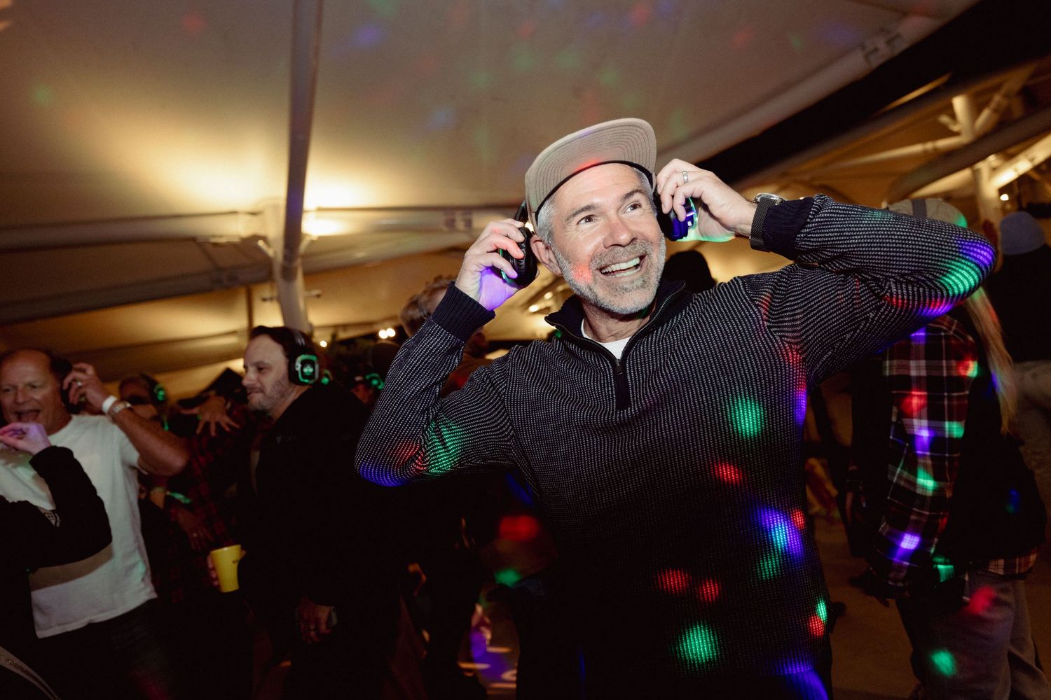 Colorful disco lights illuminate a dark venue during a lively celebration.