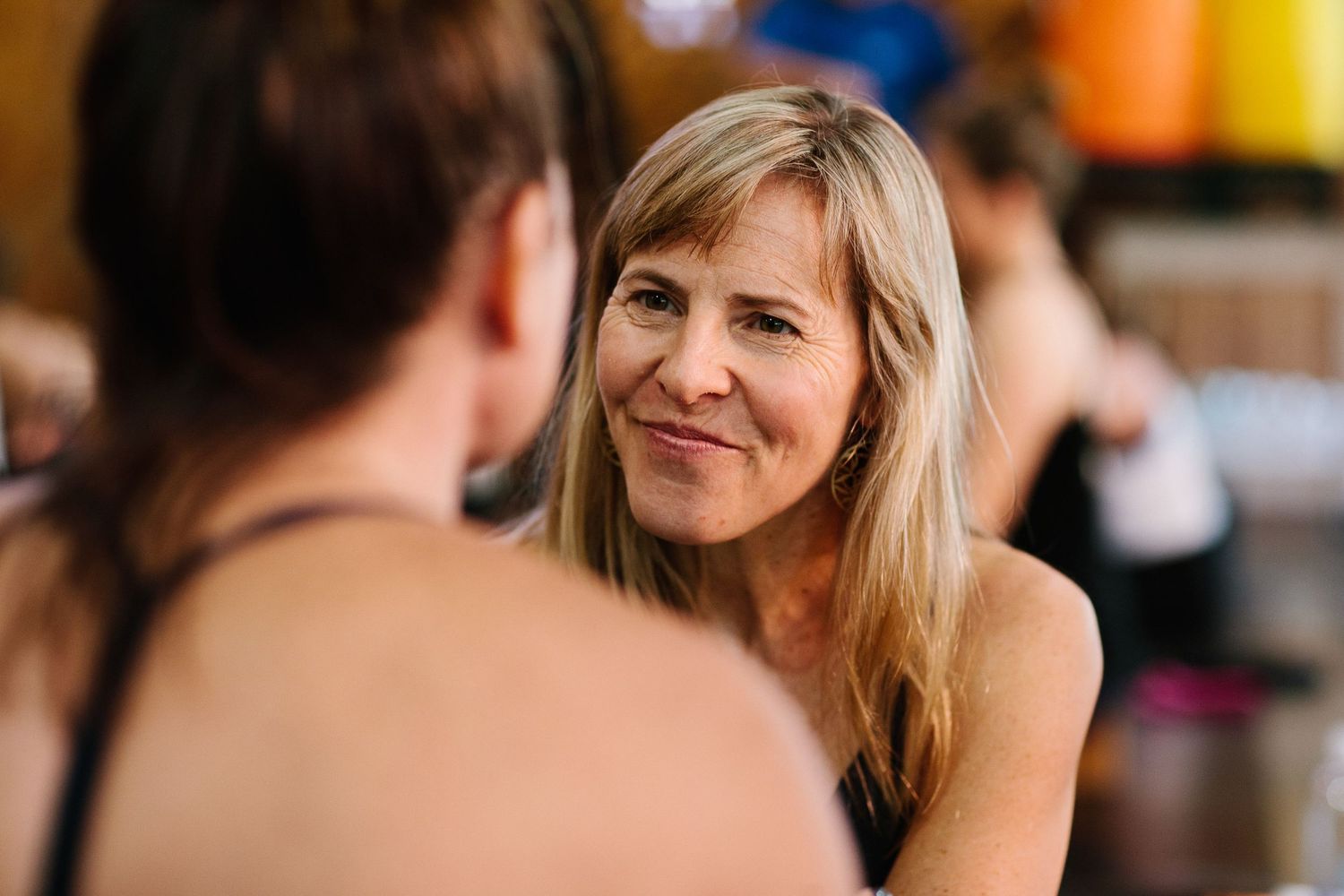 People chatting and interacting during a break at a yoga studio workshop.