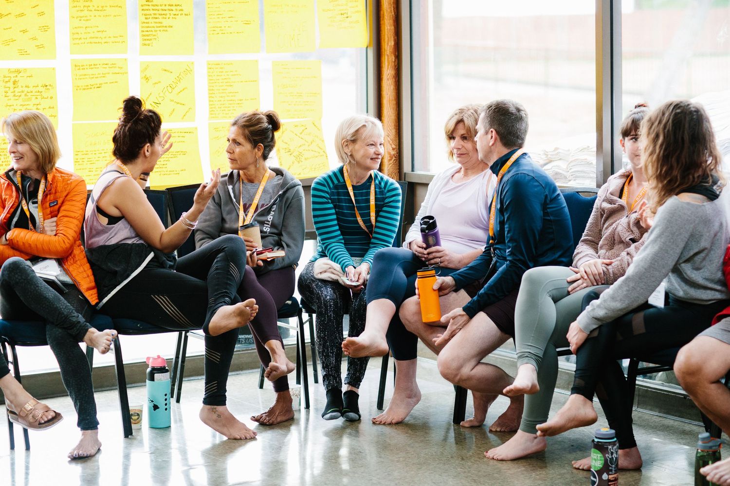 Group of fitness enthusiasts having casual conversation while seated in bright studio space.