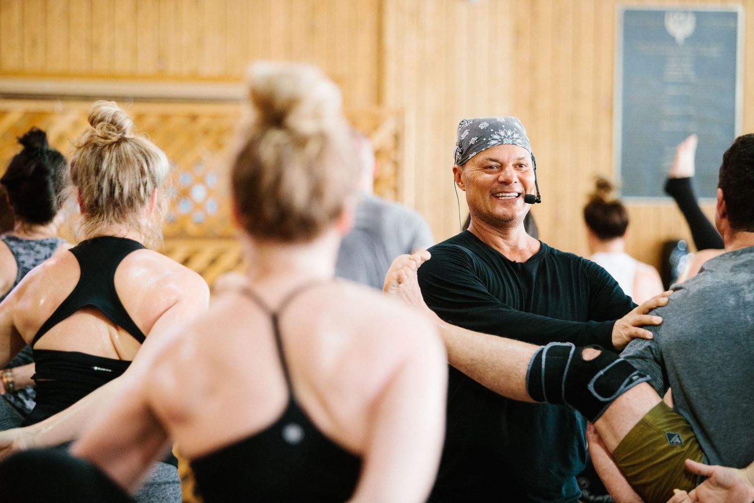 Students participating in a yoga class with instructor demonstrating poses in a well-lit studio.