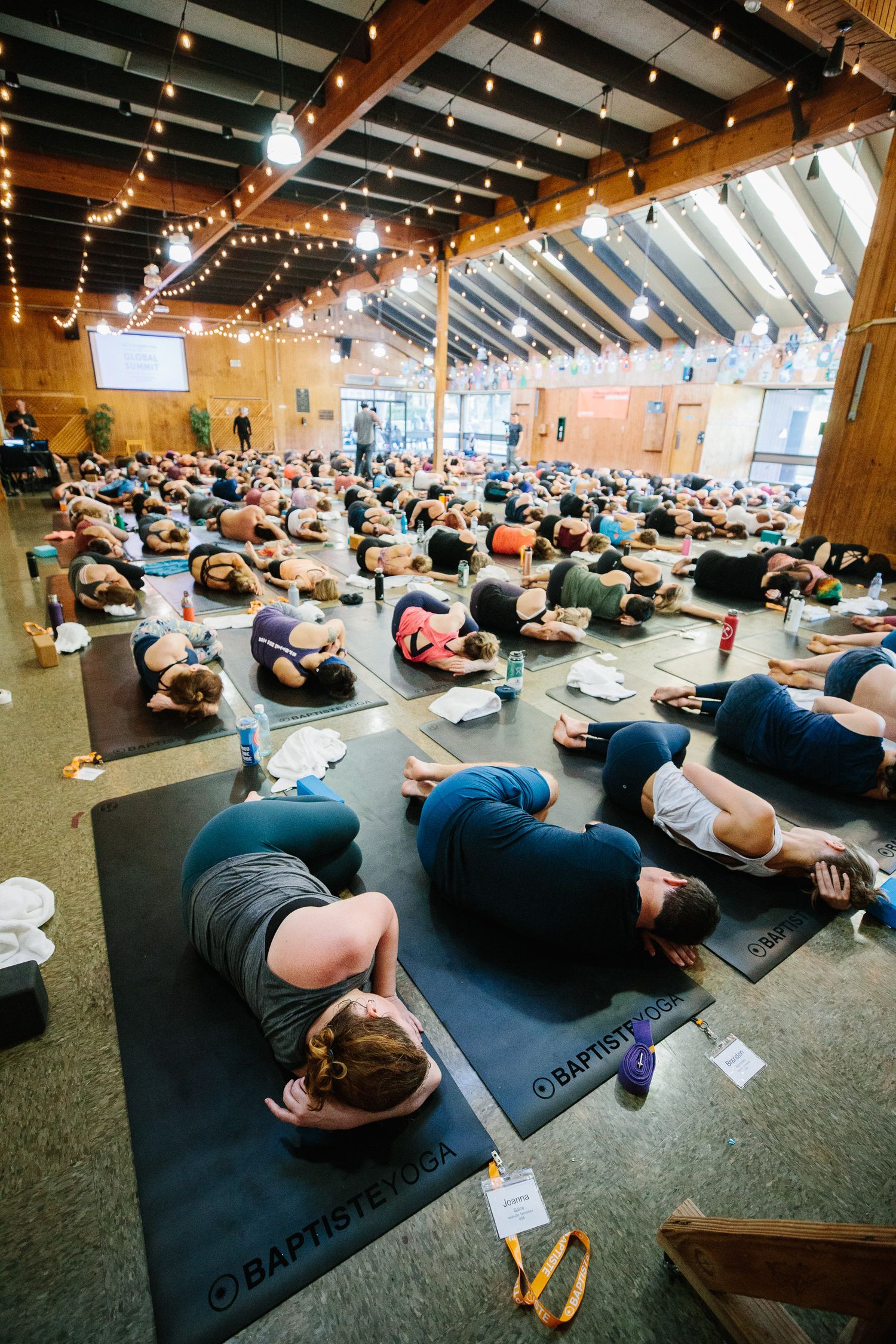 Large group lies on exercise mats during a relaxation or cool-down session in a spacious studio.